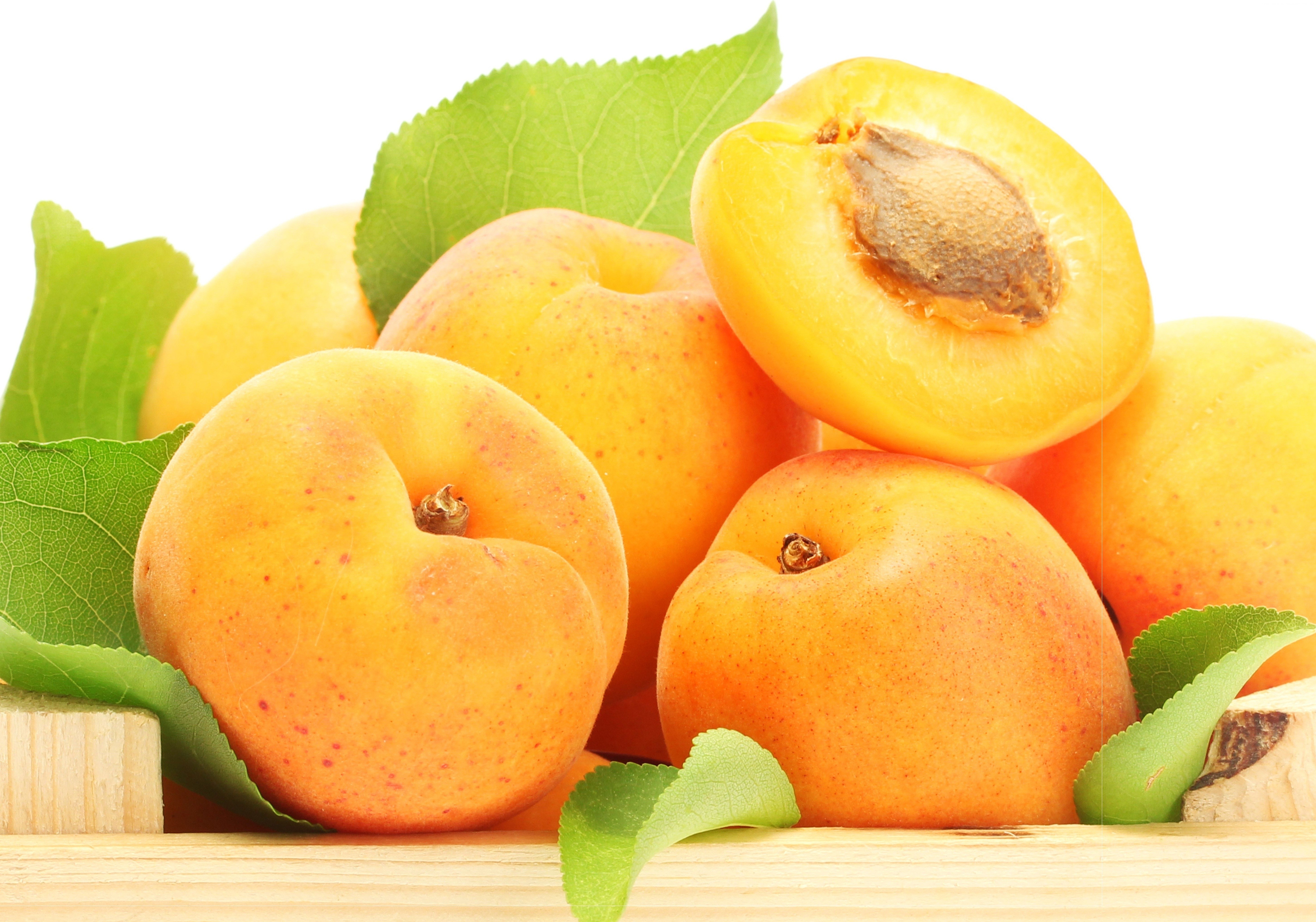 Apricots with leaves on a wooden surface HD Wallpaper