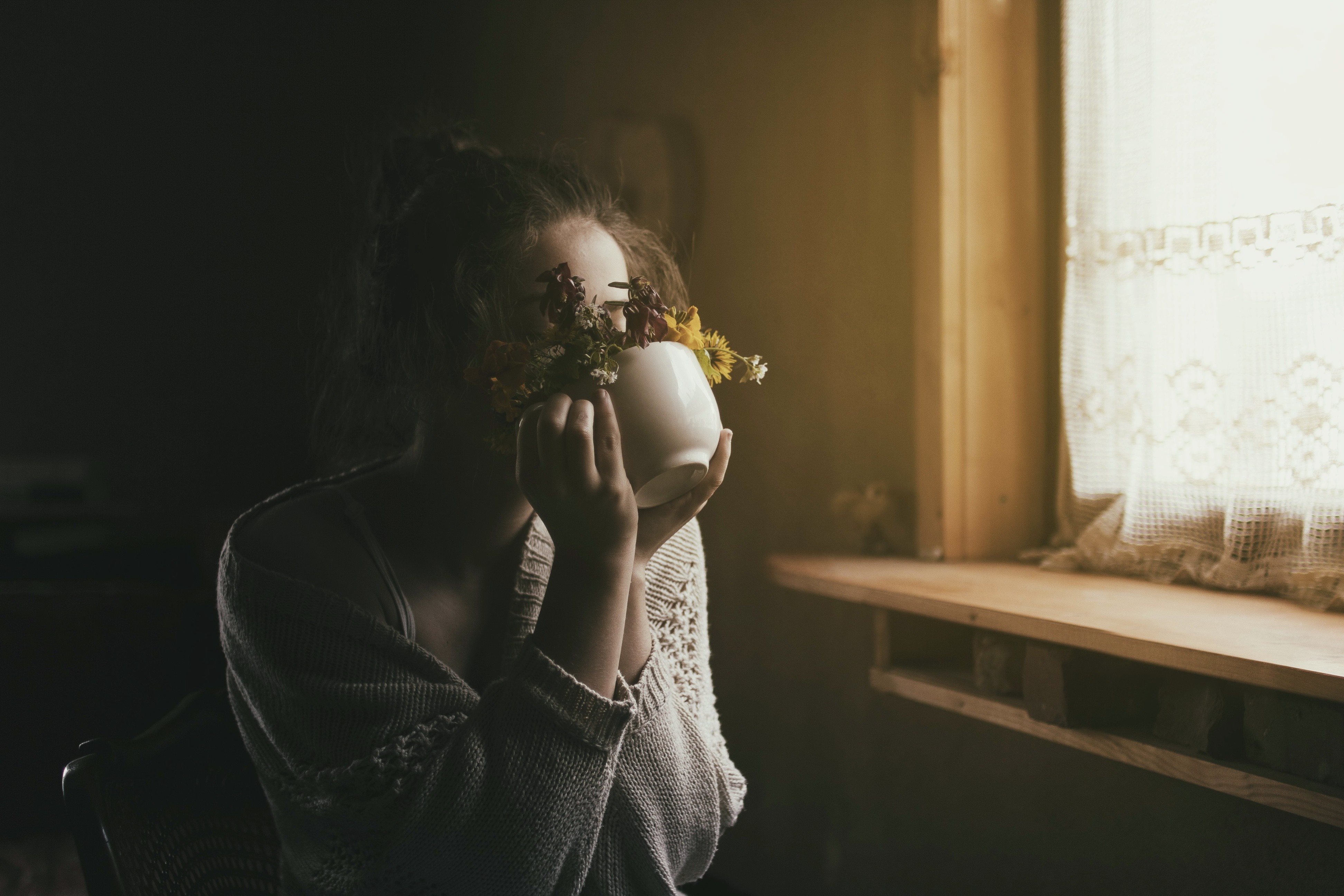 Woman holding a vase of flowers near a window HD Wallpaper