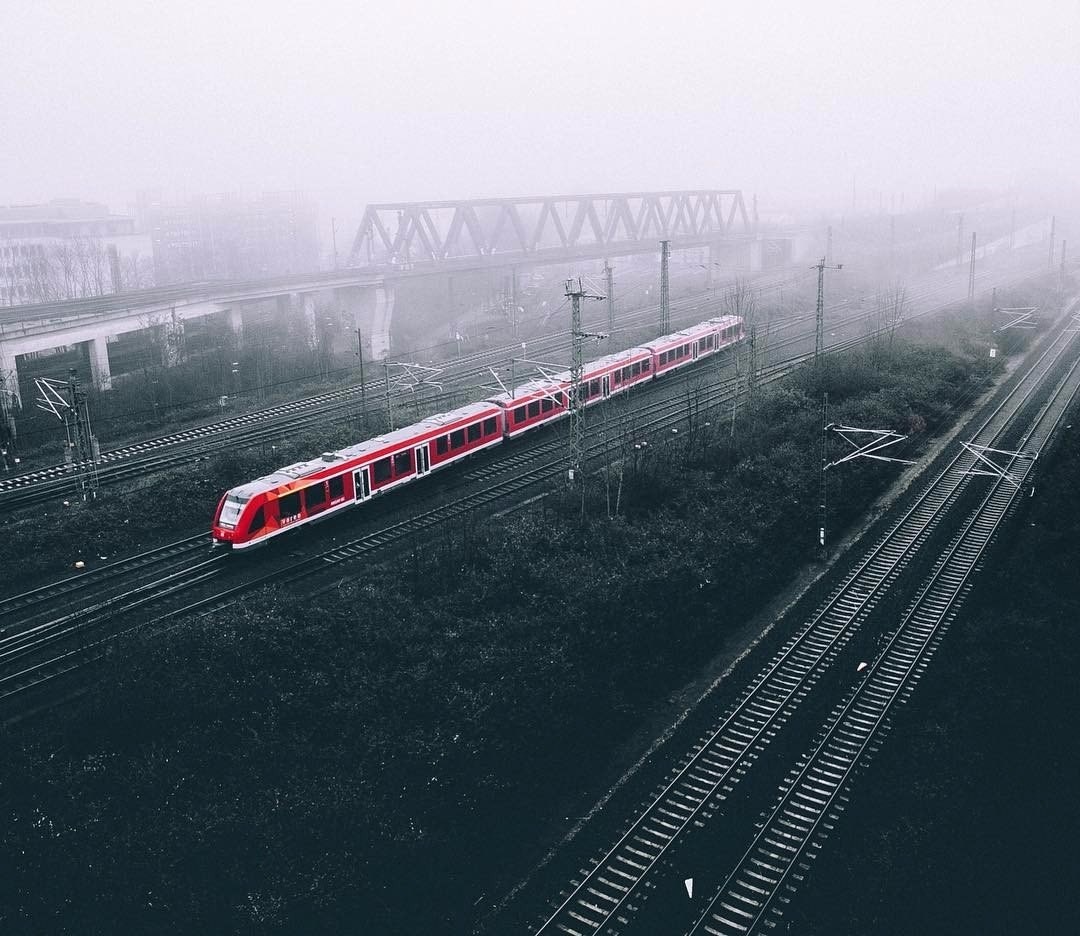 Red train on tracks in fog with bridge HD Wallpaper