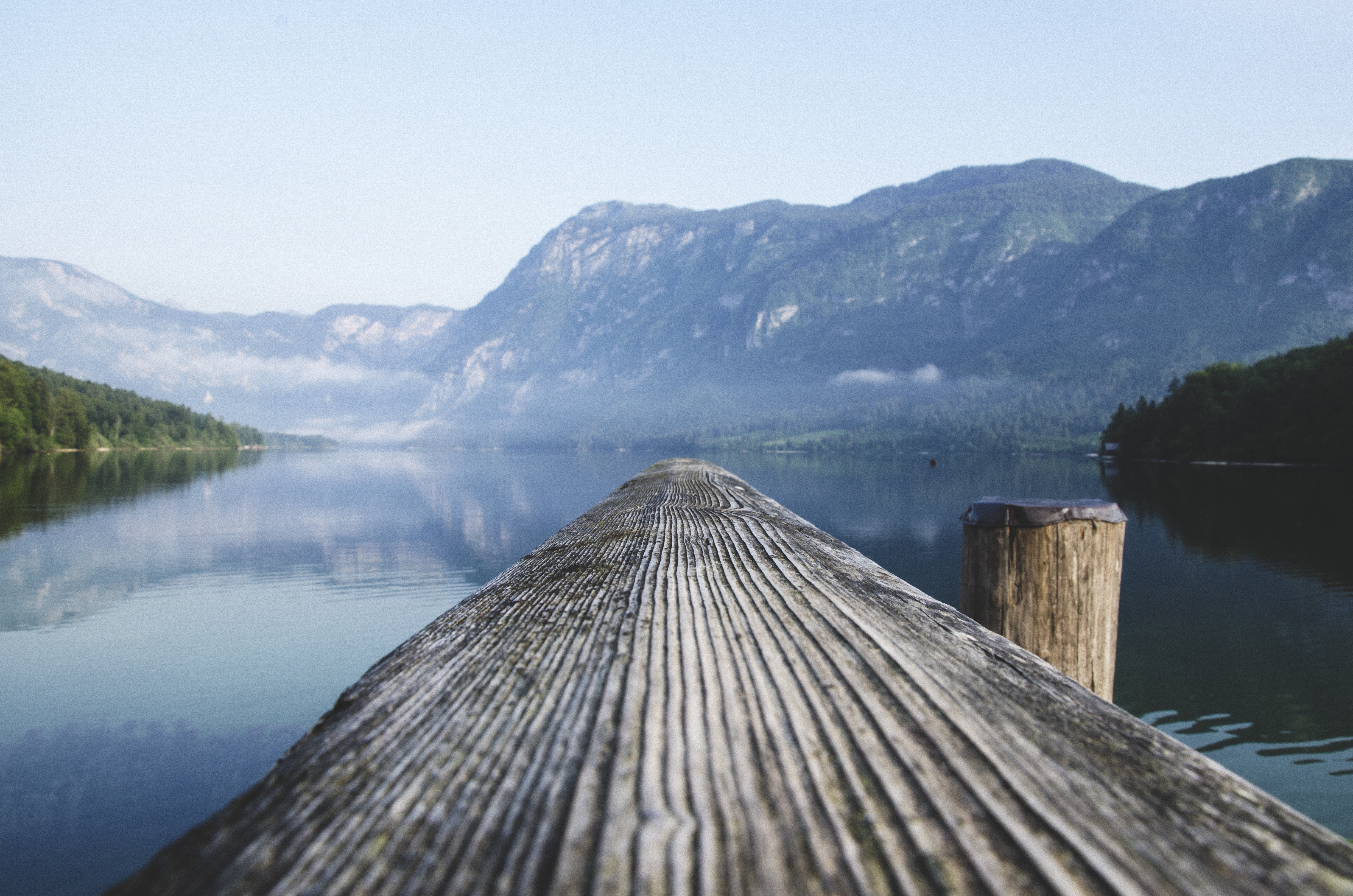 Wooden dock on a calm lake with mountains in the background HD Wallpaper