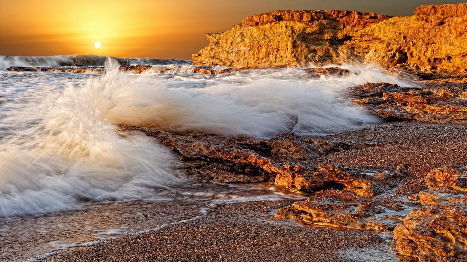 Waves crashing on rocky shore at sunset HD Wallpaper