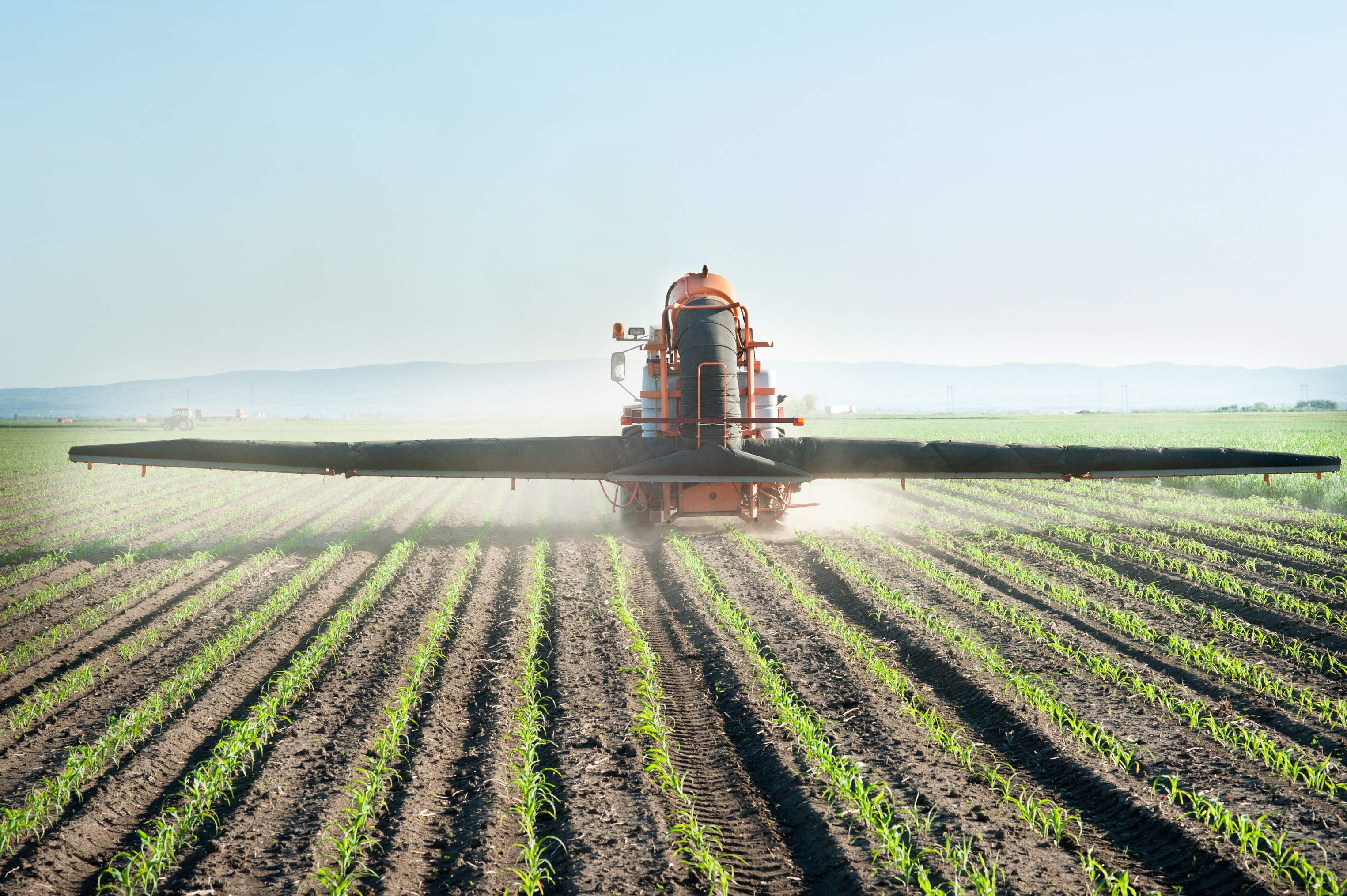 Agricultural sprayer in a young crop field HD Wallpaper