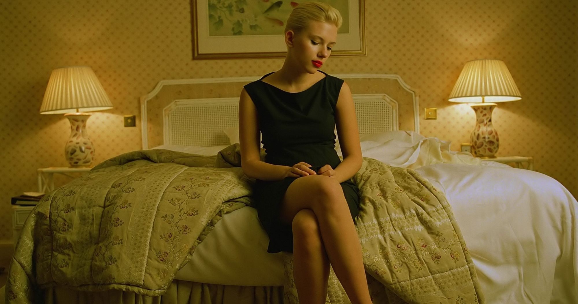 Scarlett Johansson in a black dress sitting on a bed HD Wallpaper