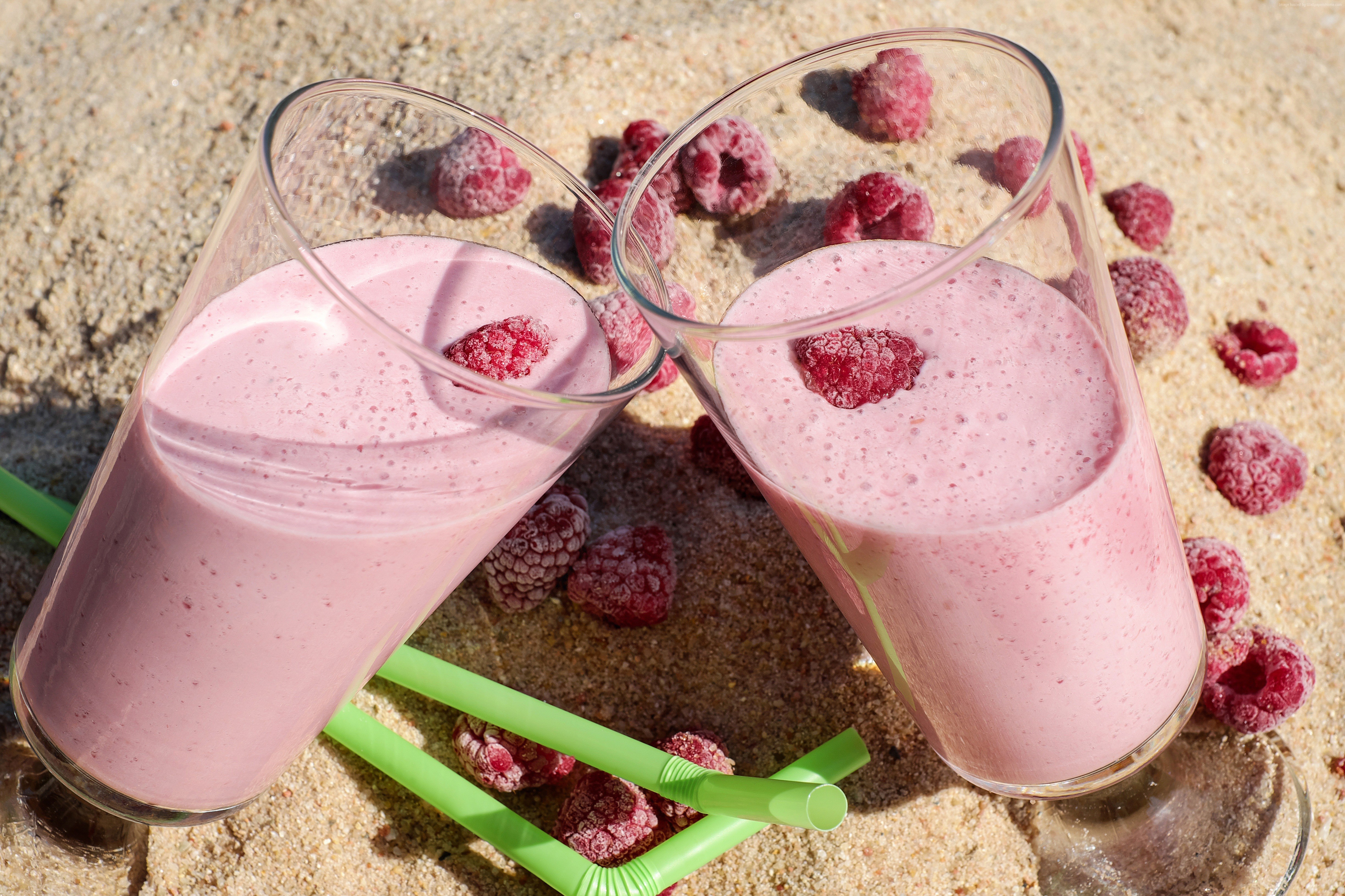 Two raspberry cocktails on sand with raspberries HD Wallpaper