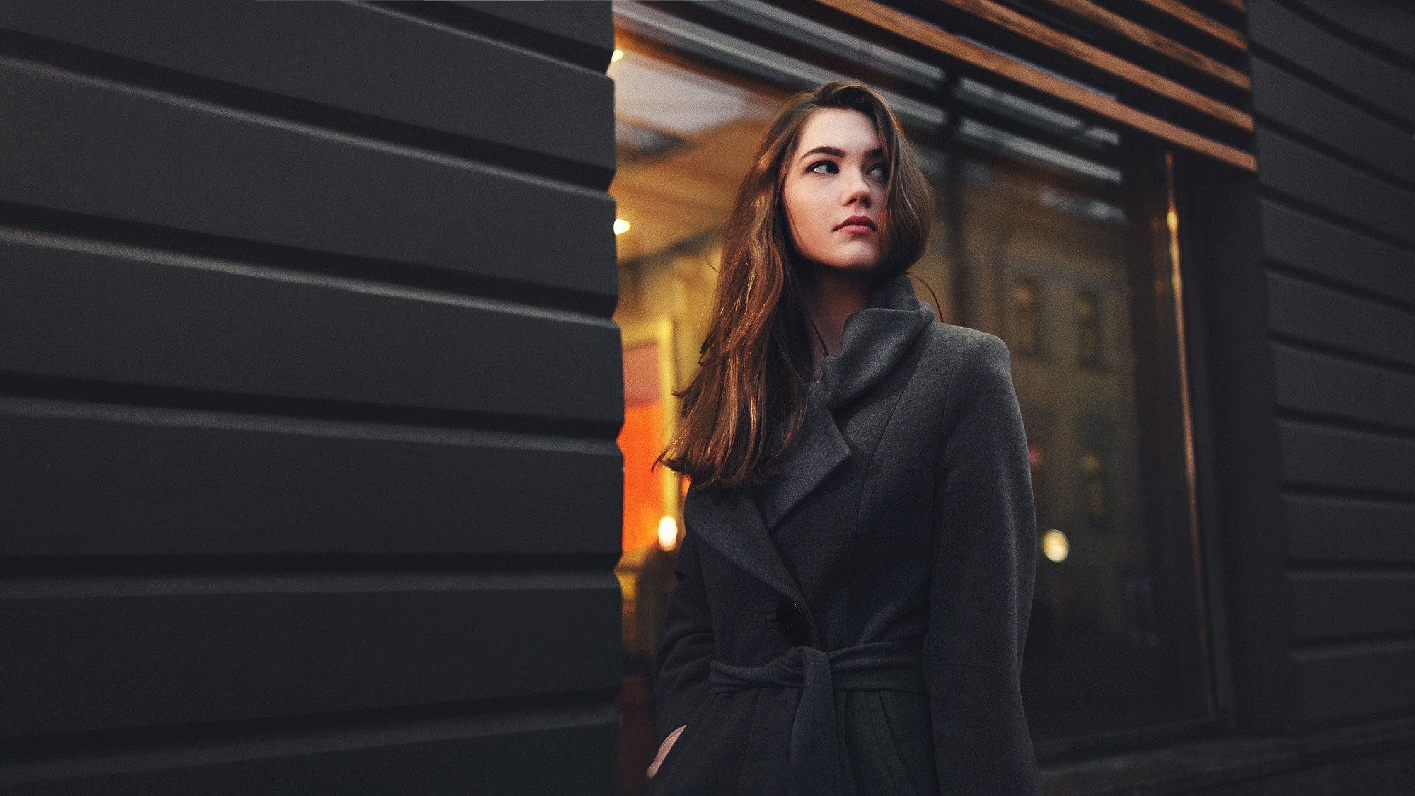 Woman in a dark coat standing outside a building HD Wallpaper