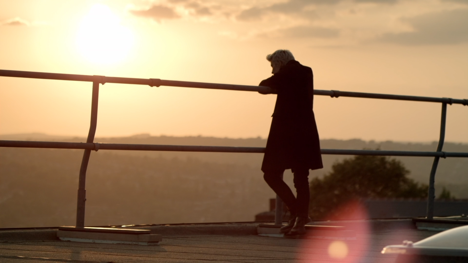 Man leaning on railing at sunset HD Wallpaper
