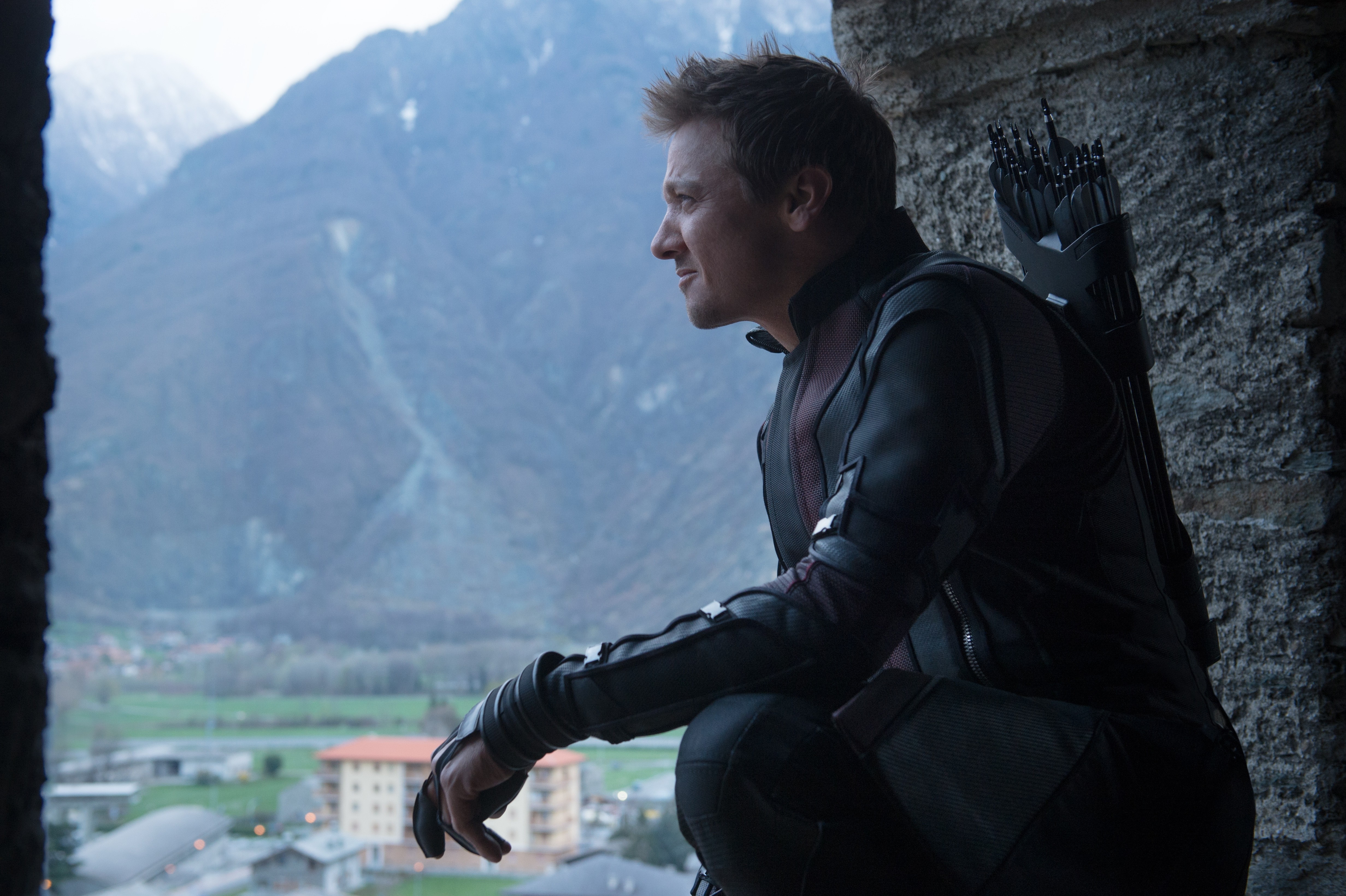 Hawkeye from The Avengers crouches by a stone wall HD Wallpaper