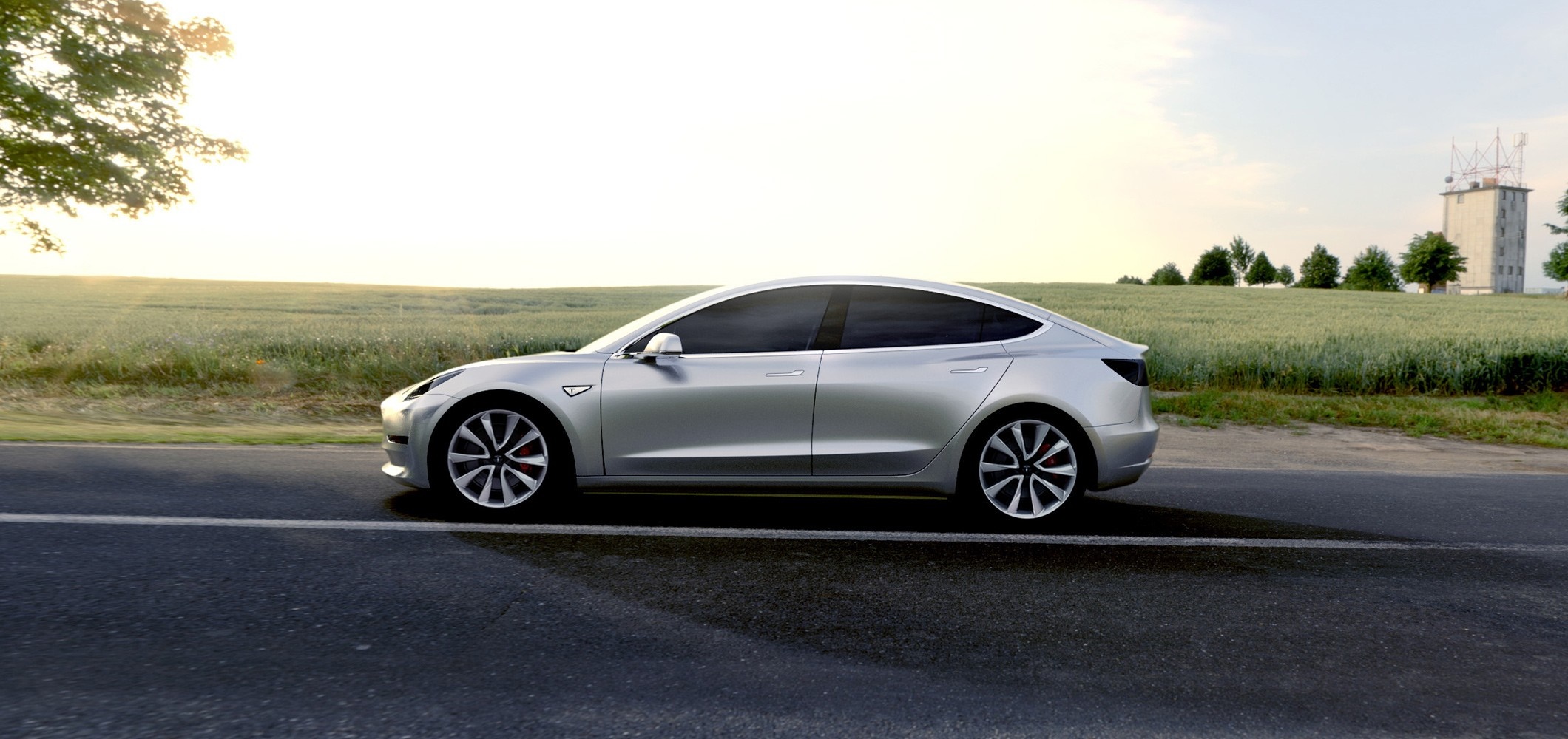 Silver Tesla Model 3 driving on a road near a field HD Wallpaper