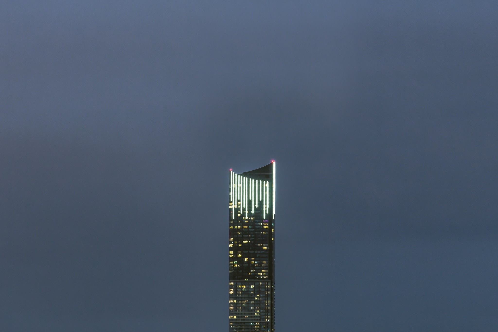 Skyscraper with lights against a dark sky HD Wallpaper