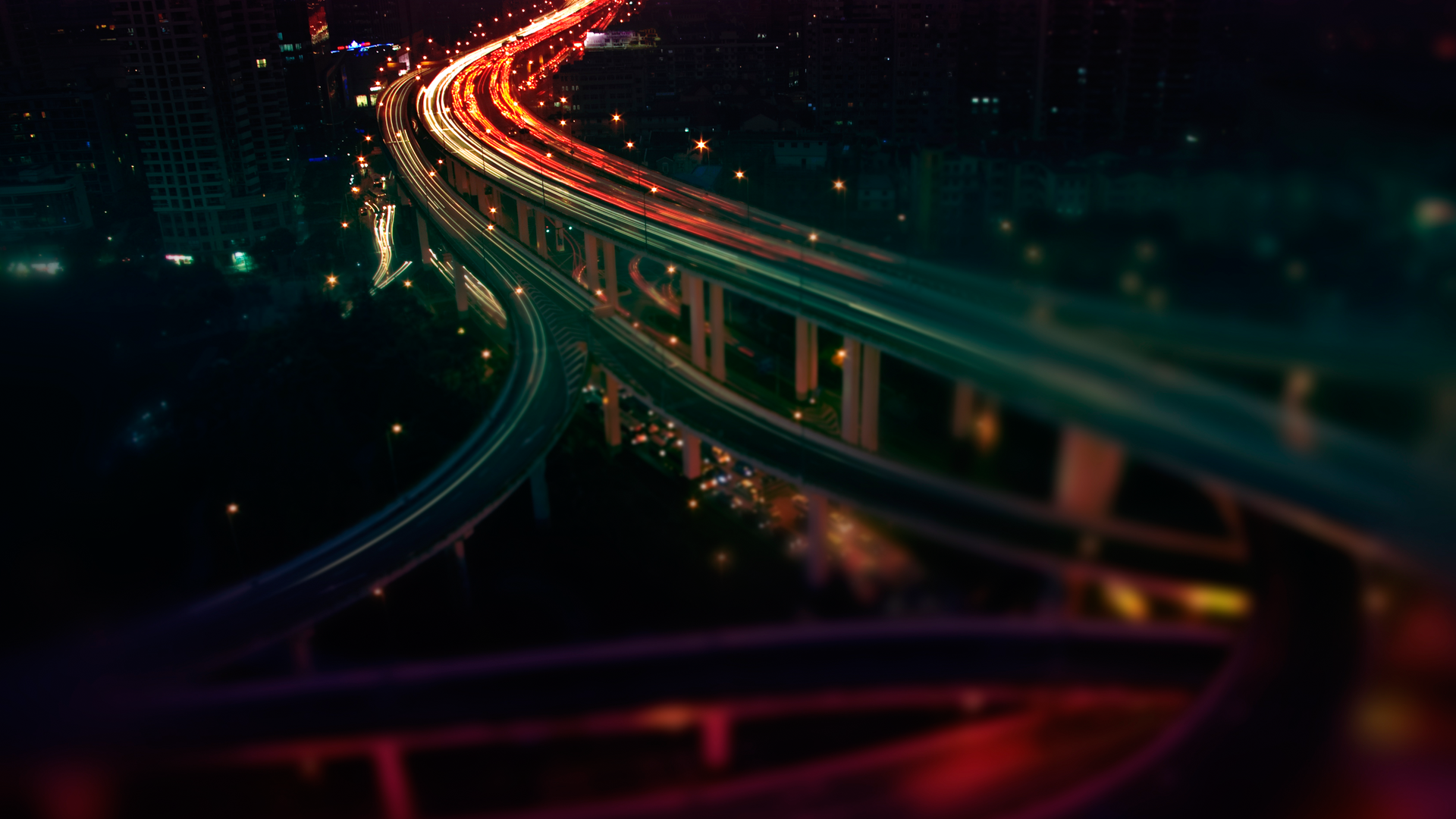 Cityscape at night with light trails on highways HD Wallpaper