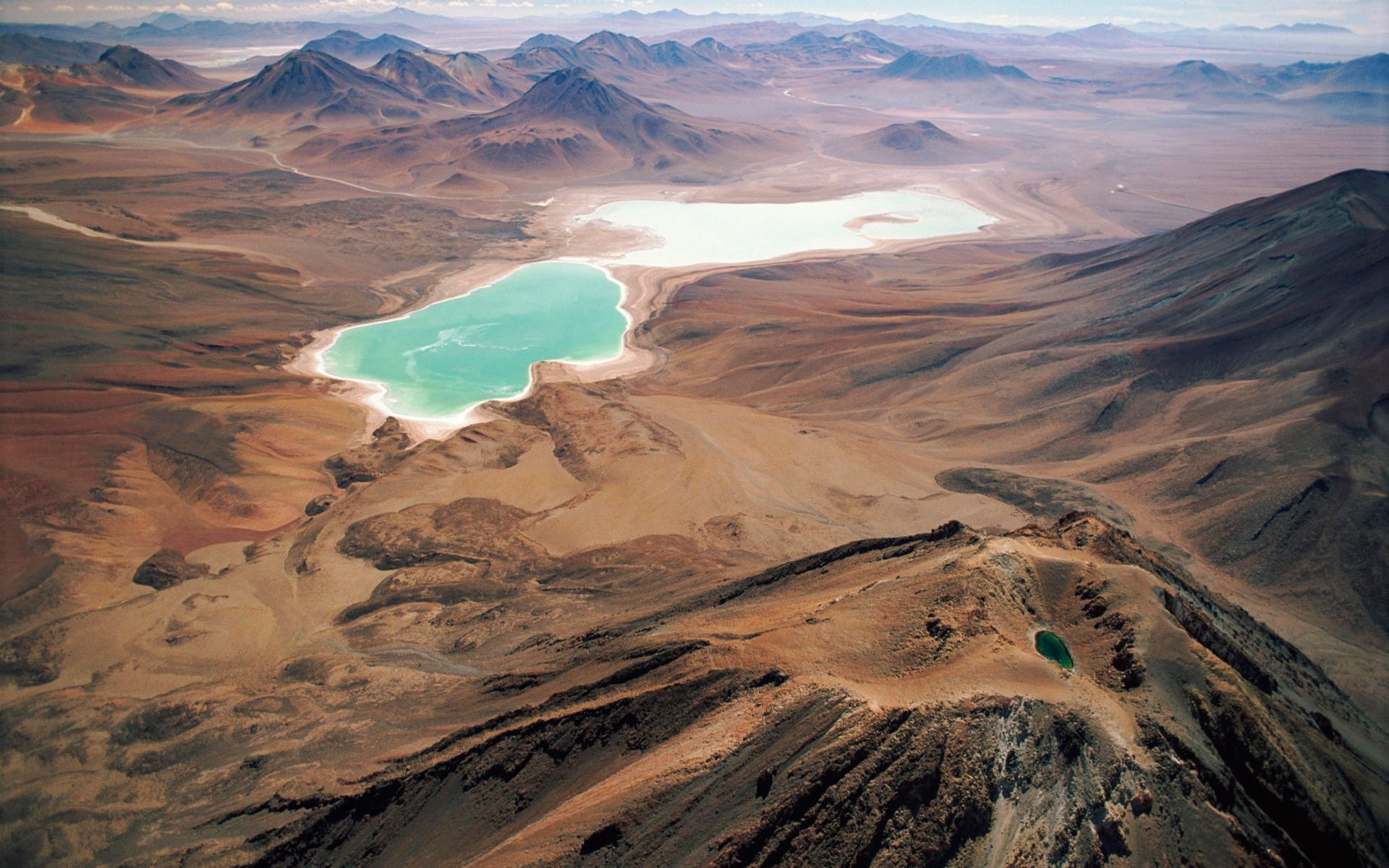 Aerial view of a turquoise lake in a desert landscape HD Wallpaper