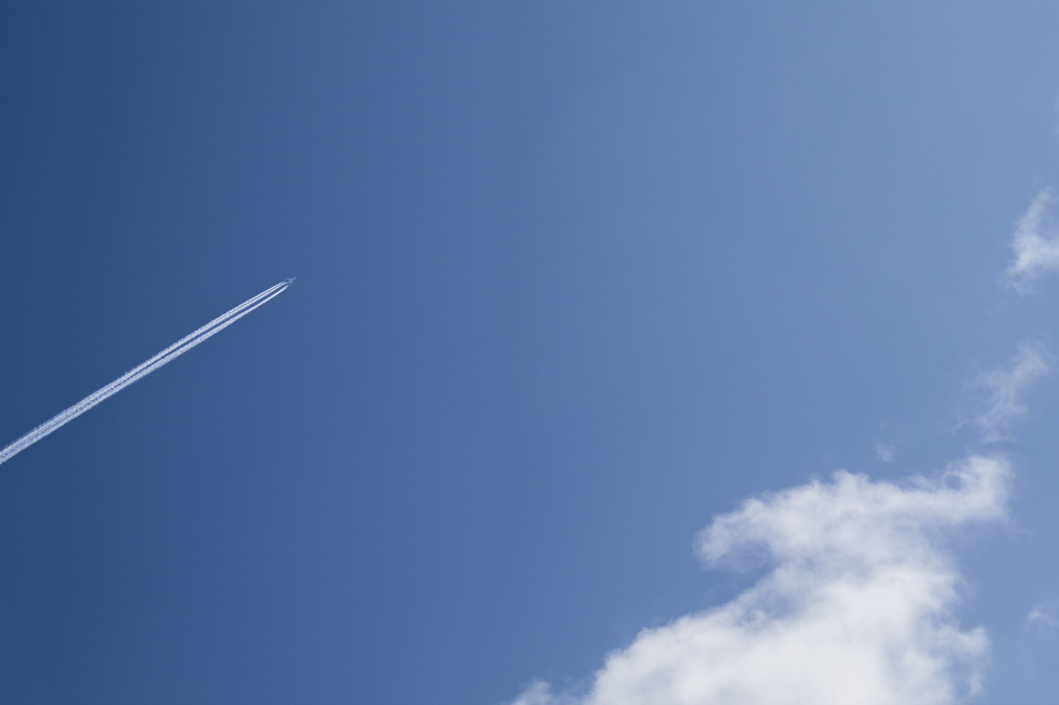 Airplane leaving a contrail in a blue sky with clouds HD Wallpaper