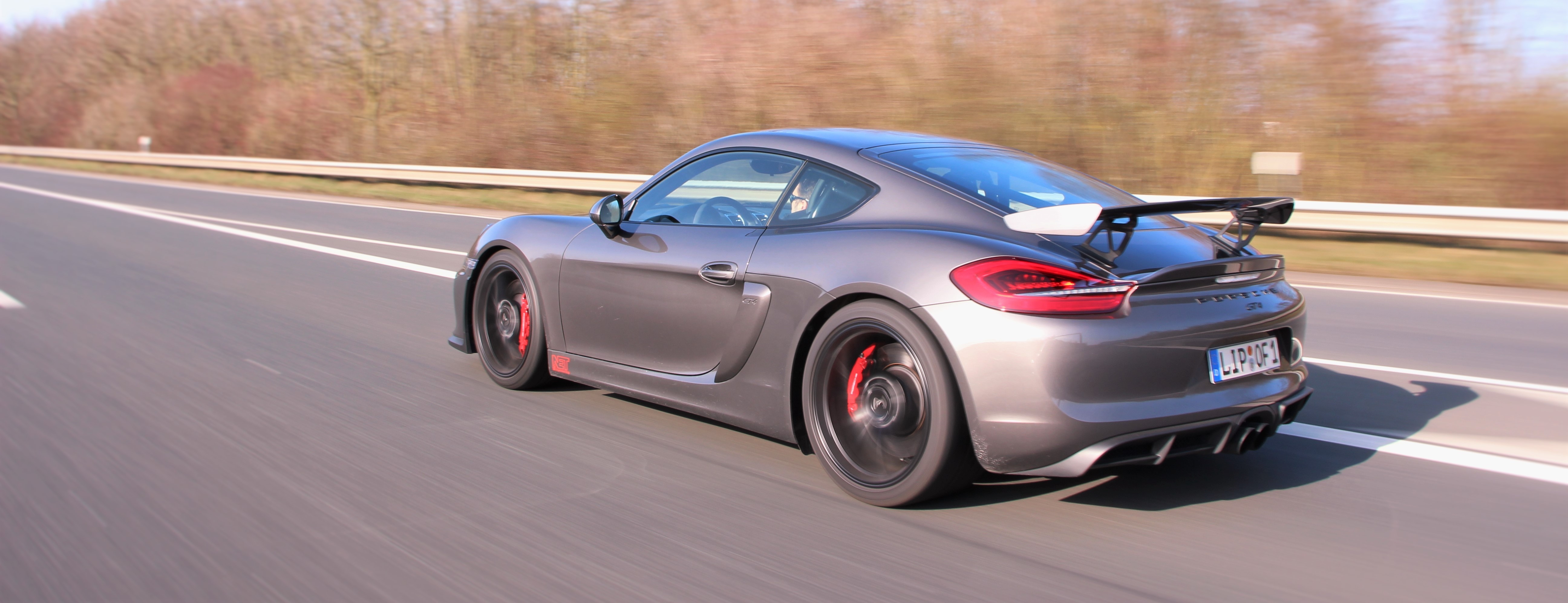 Porsche Cayman GT4 driving on a highway HD Wallpaper