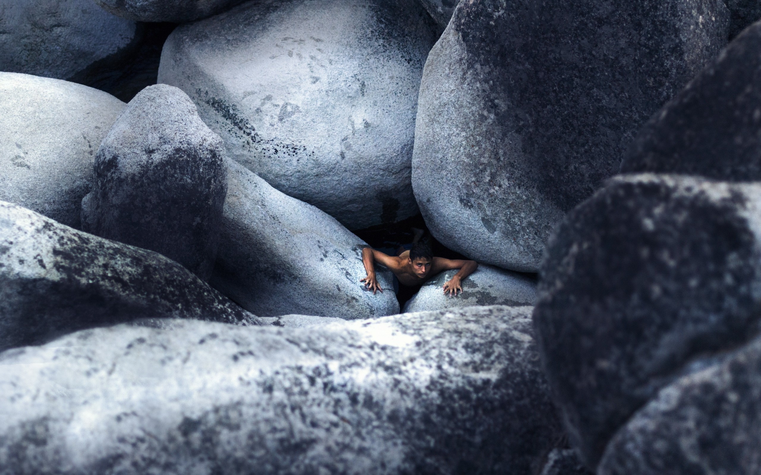 Man climbing between large rocks HD Wallpaper