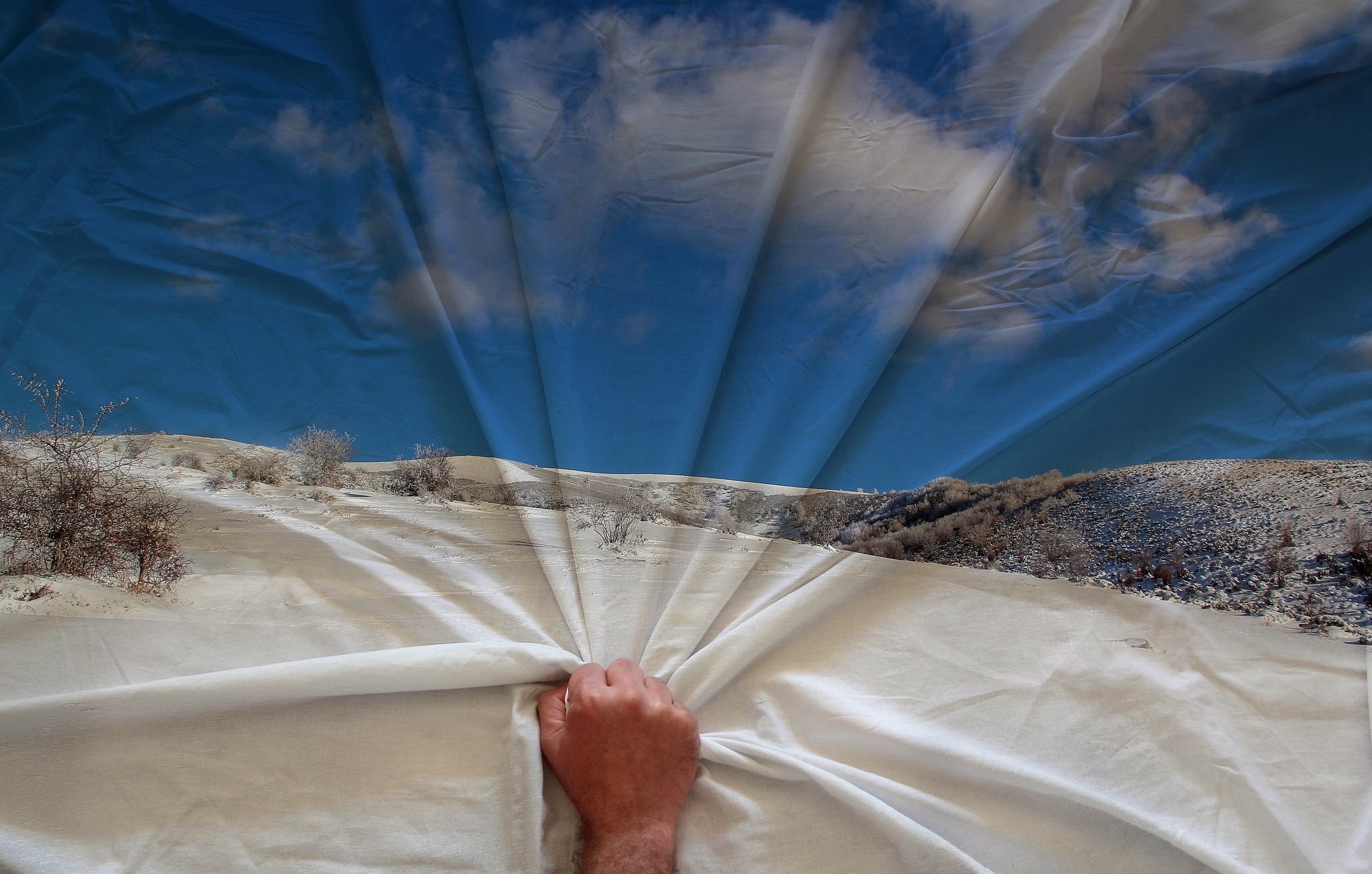 Hand pulling a sheet revealing a snowy landscape HD Wallpaper
