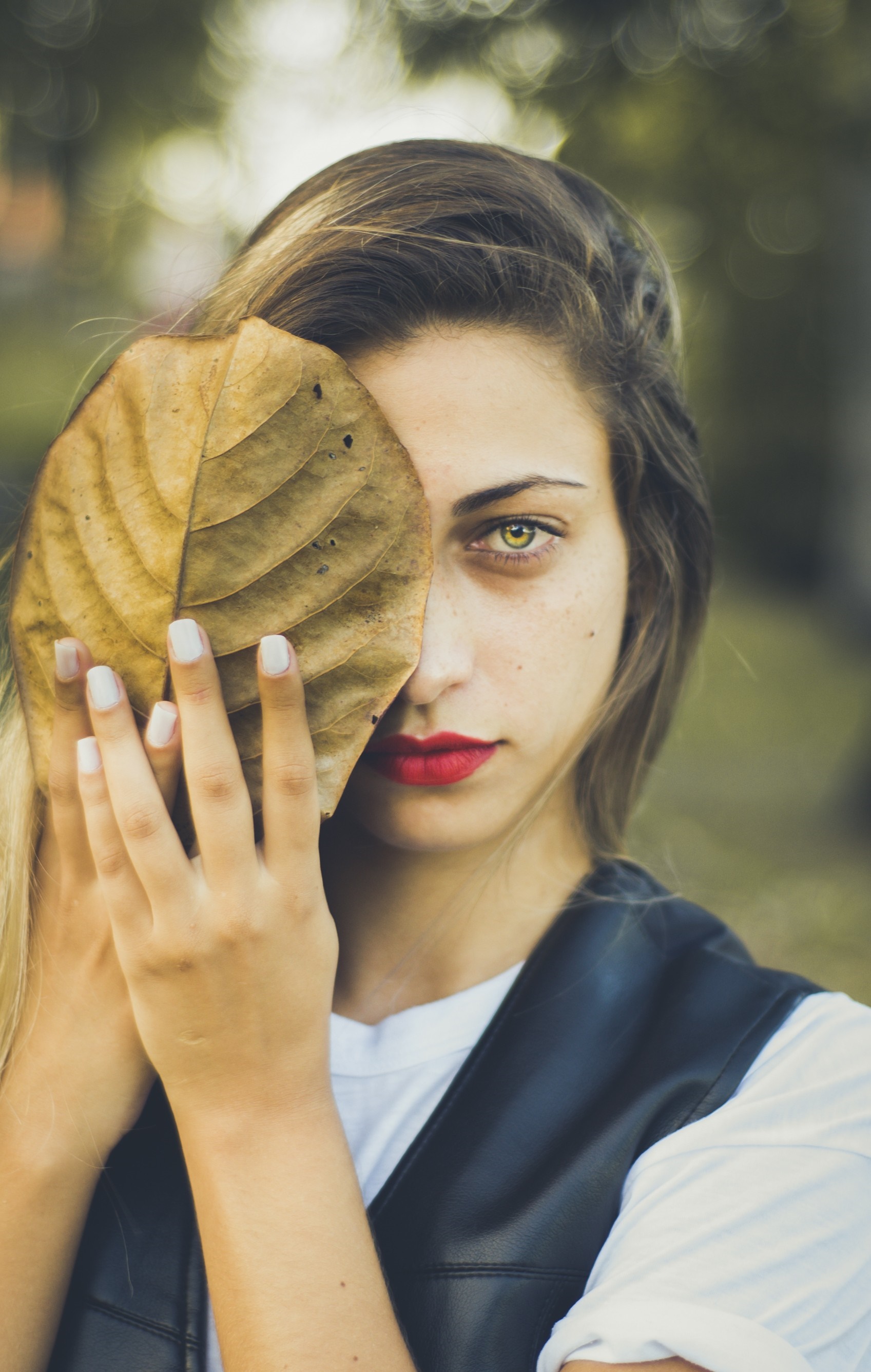 Woman holding a large leaf over her face HD Wallpaper