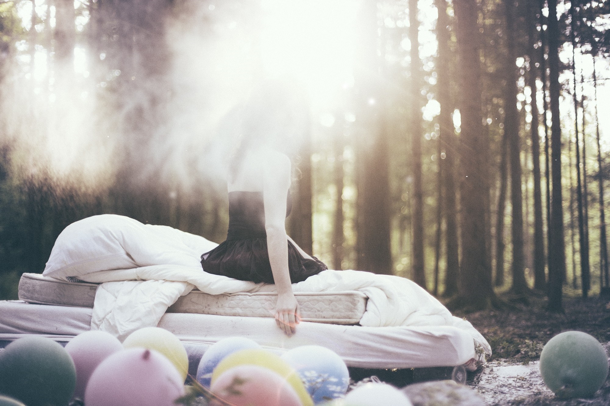 Woman in black dress on bed in forest with balloons HD Wallpaper