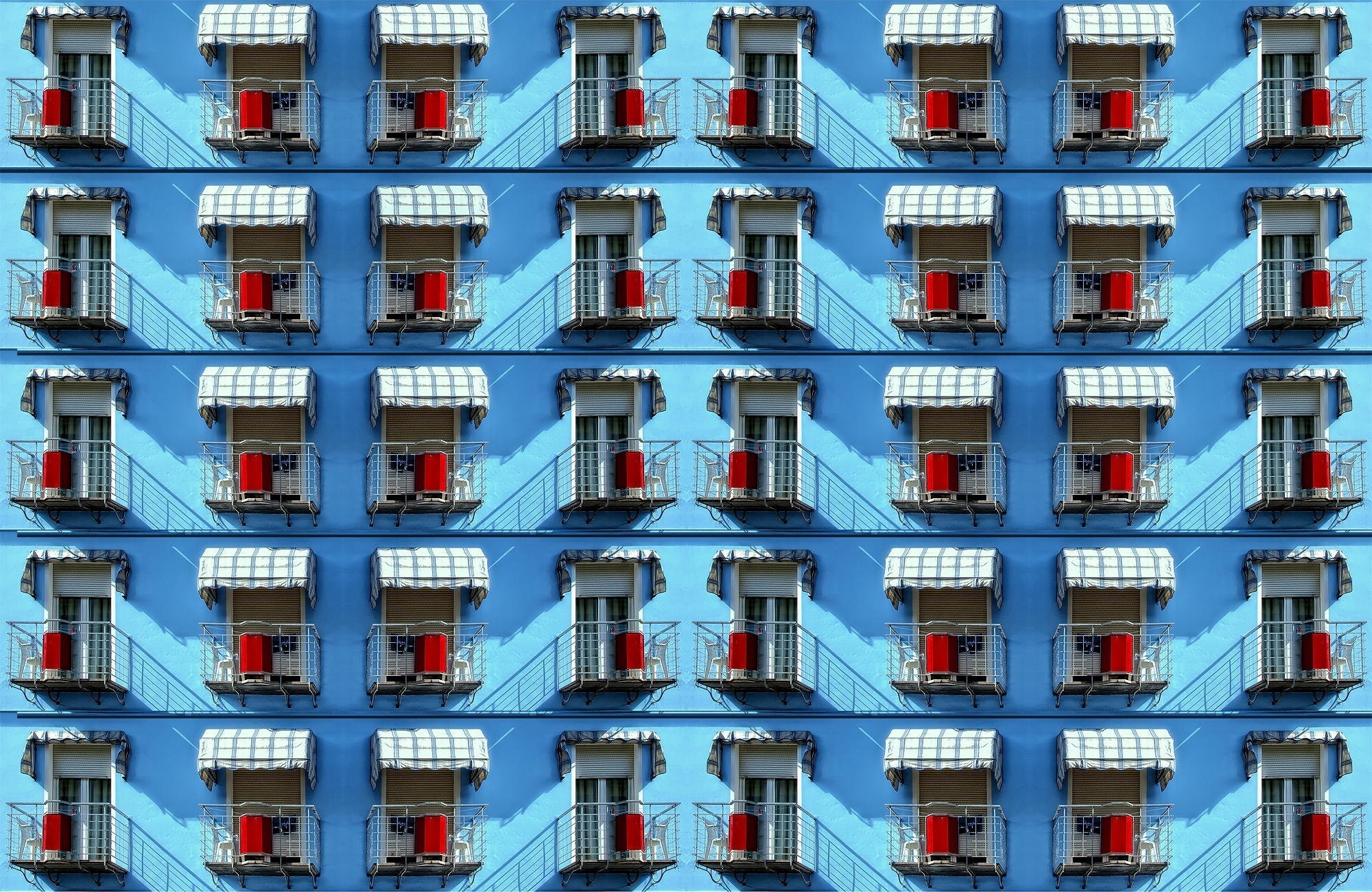 Pattern of blue building facade with balconies and red buckets HD Wallpaper