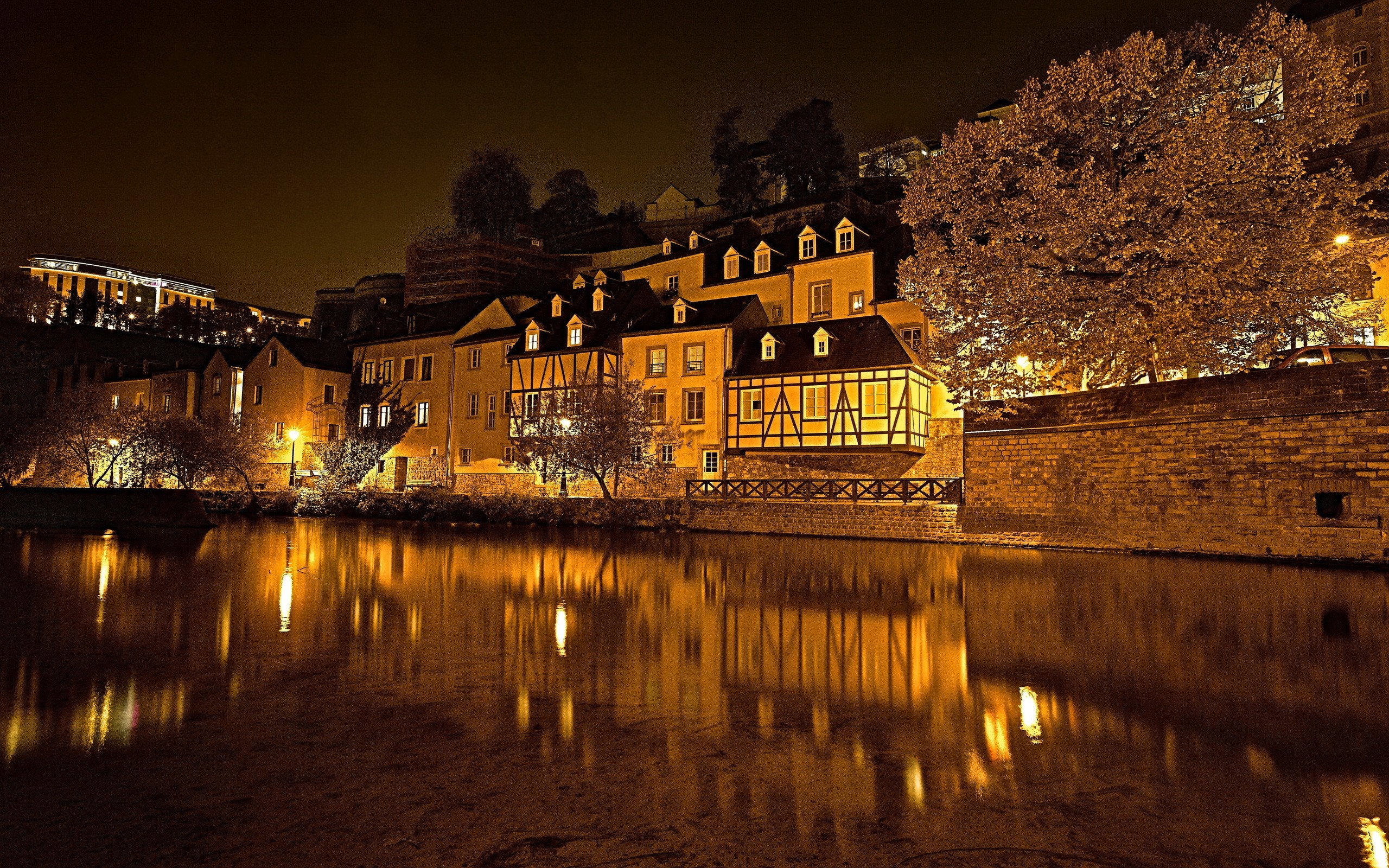Night cityscape with illuminated buildings and river reflection HD Wallpaper