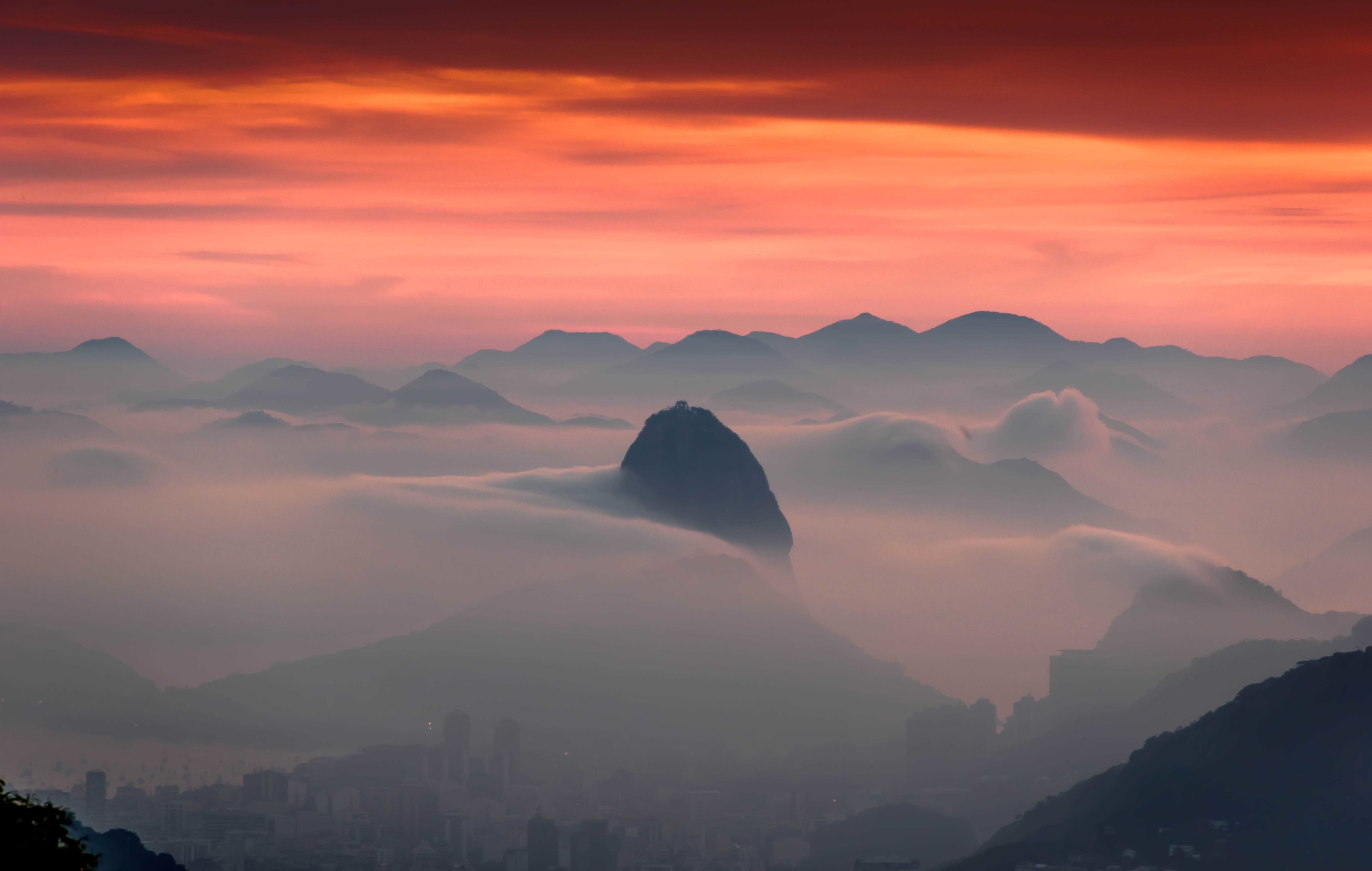 Mountain range shrouded in mist at sunset HD Wallpaper