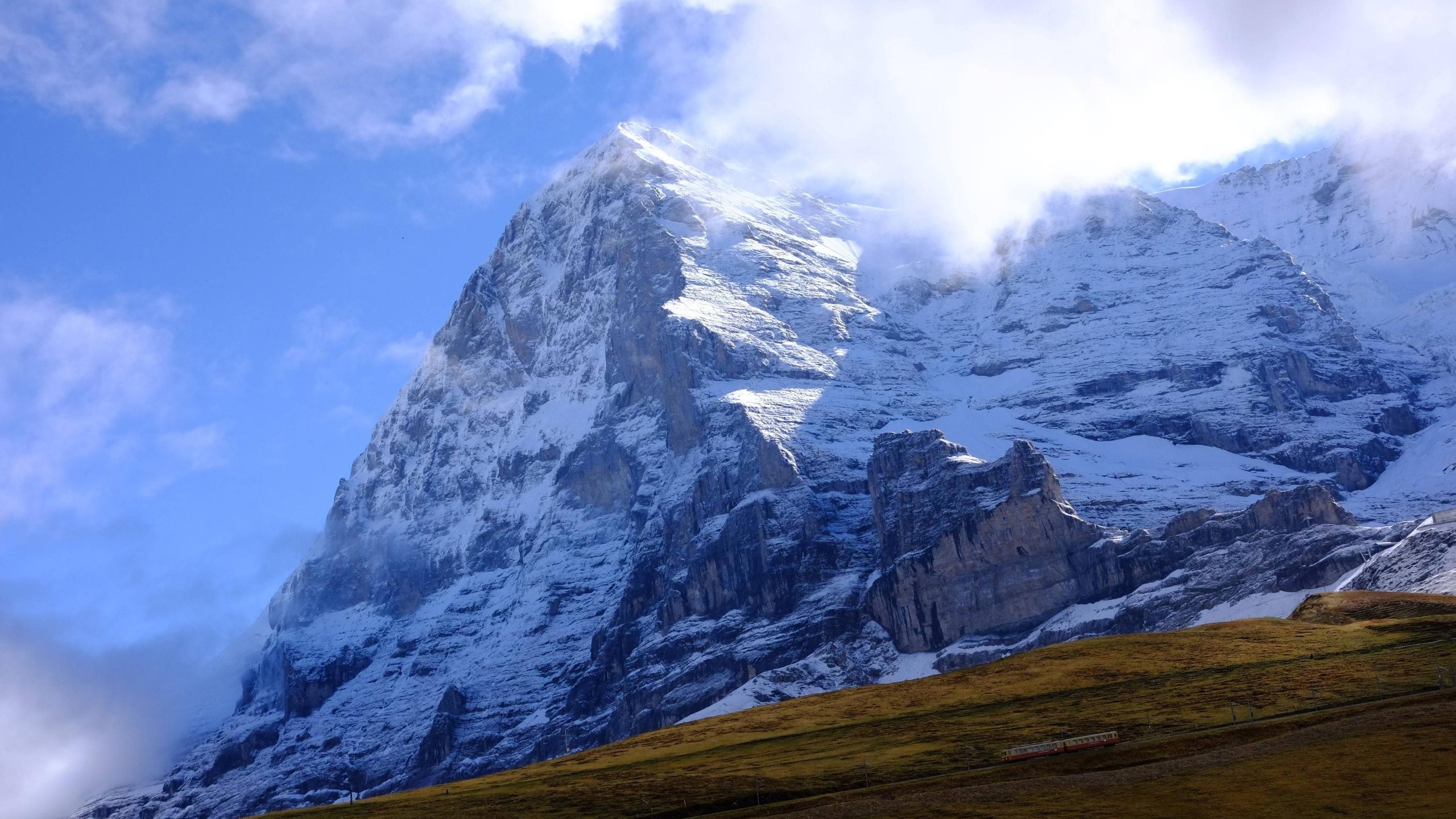 Snow-covered mountain peak with a train in the valley HD Wallpaper