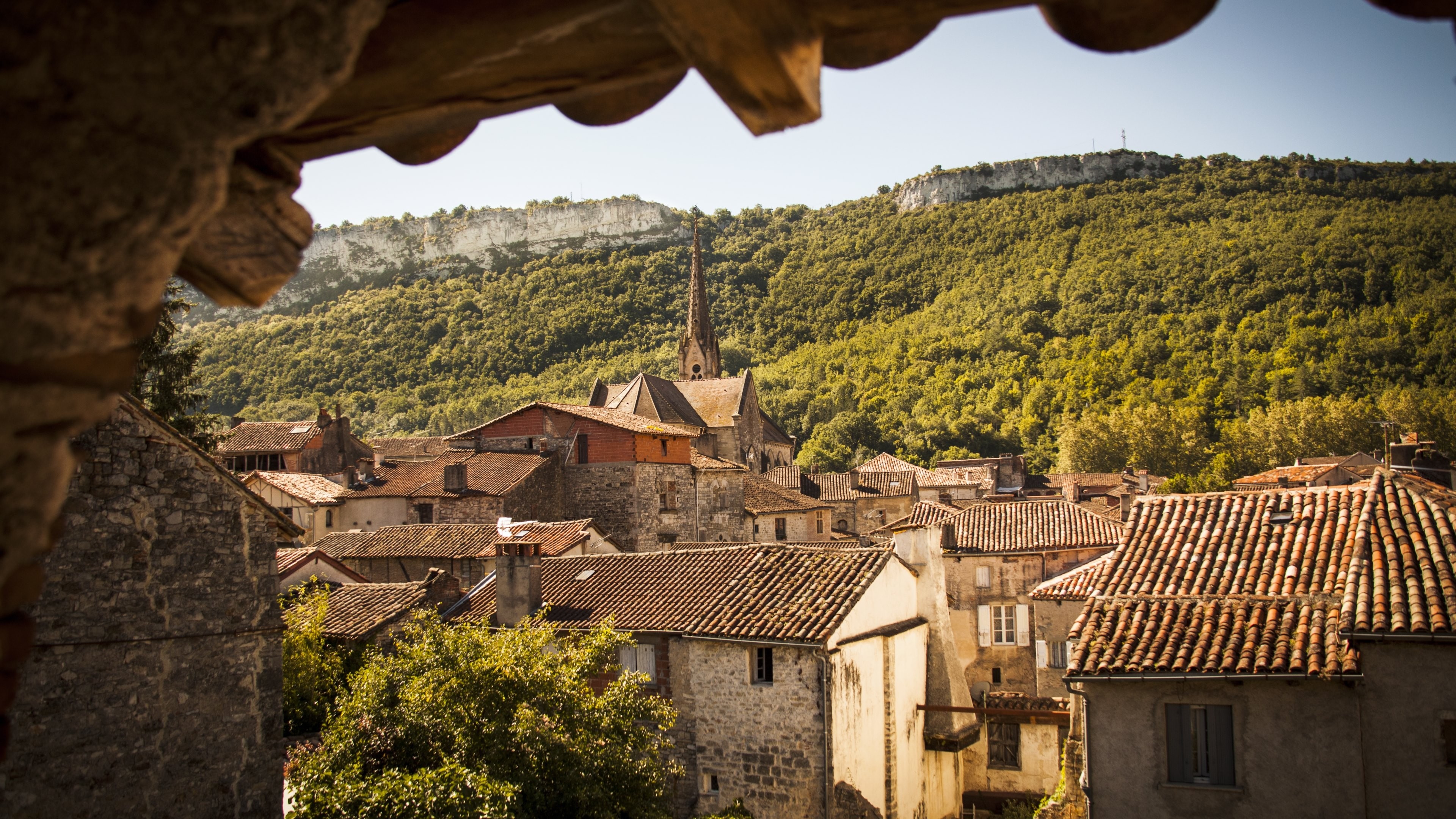 Village with church and forested hills in France HD Wallpaper