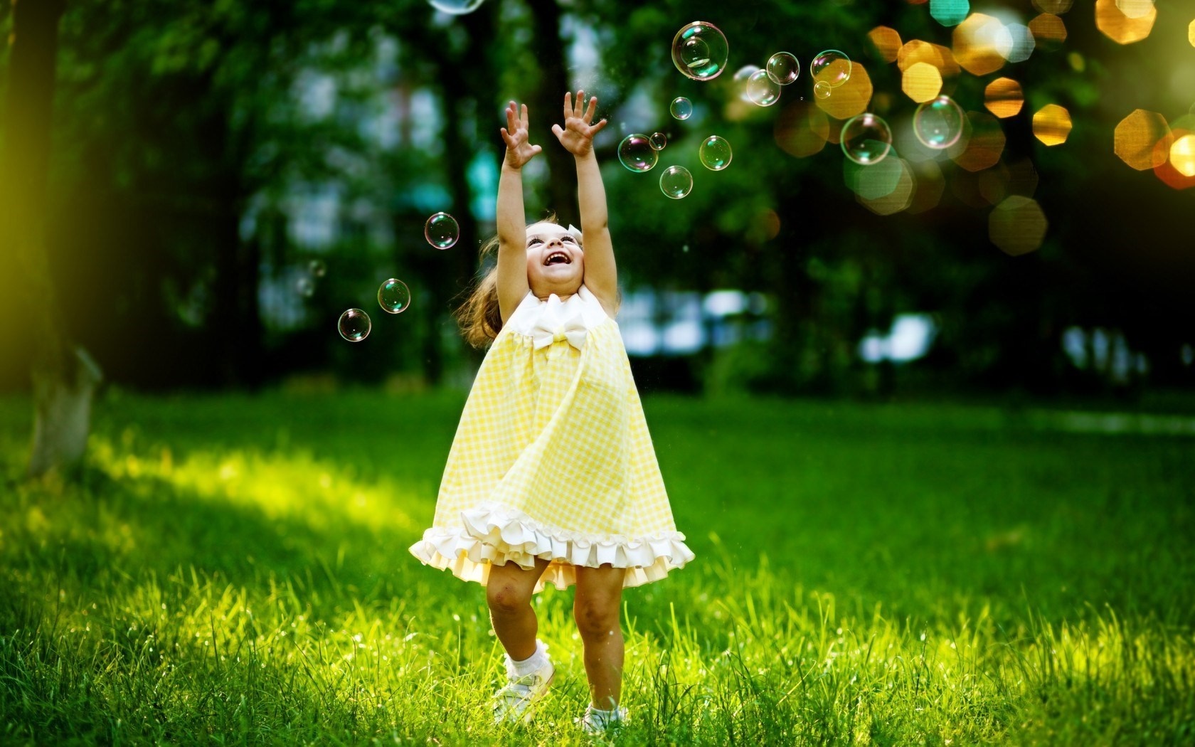 Little girl in yellow dress playing with bubbles in sunlight HD Wallpaper