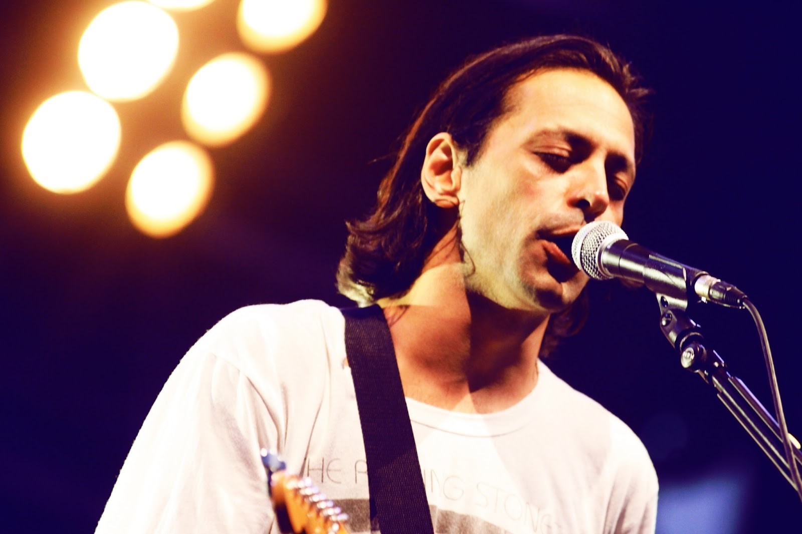 Man singing into a microphone on stage HD Wallpaper