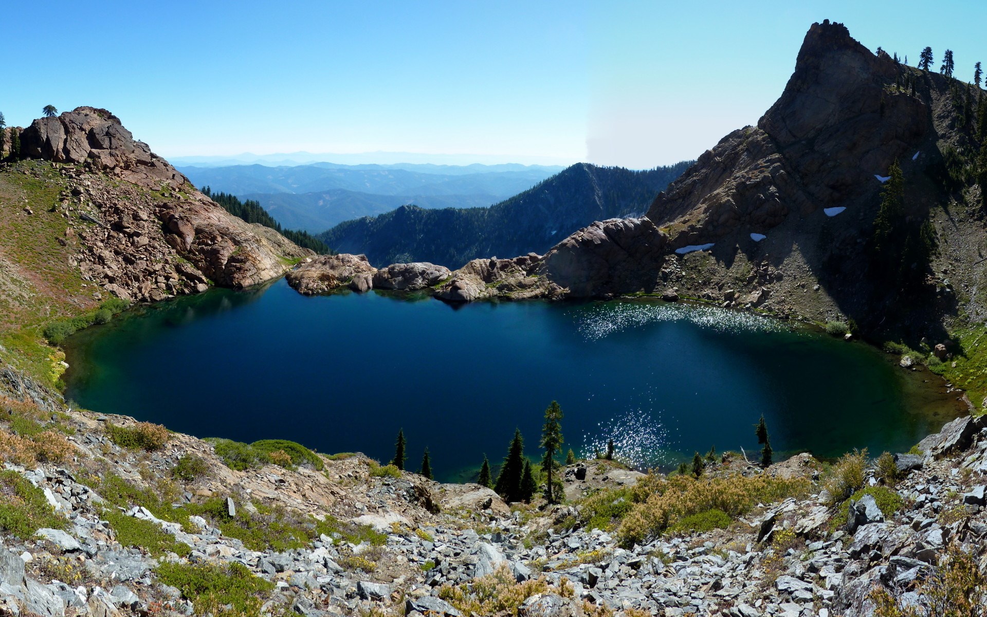Deep blue alpine lake surrounded by rocky mountains HD Wallpaper