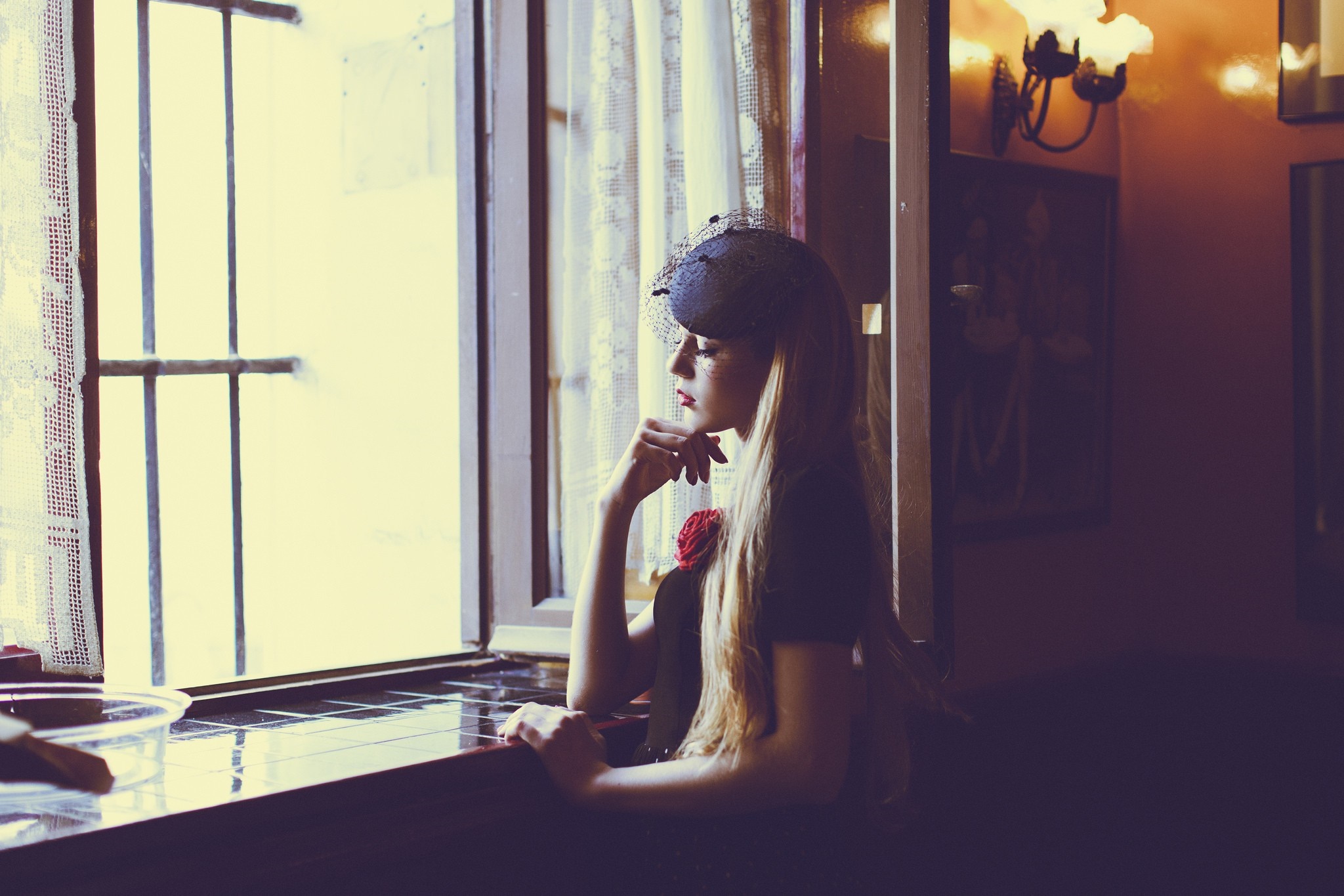 Woman in black hat and dress with red flower by window HD Wallpaper