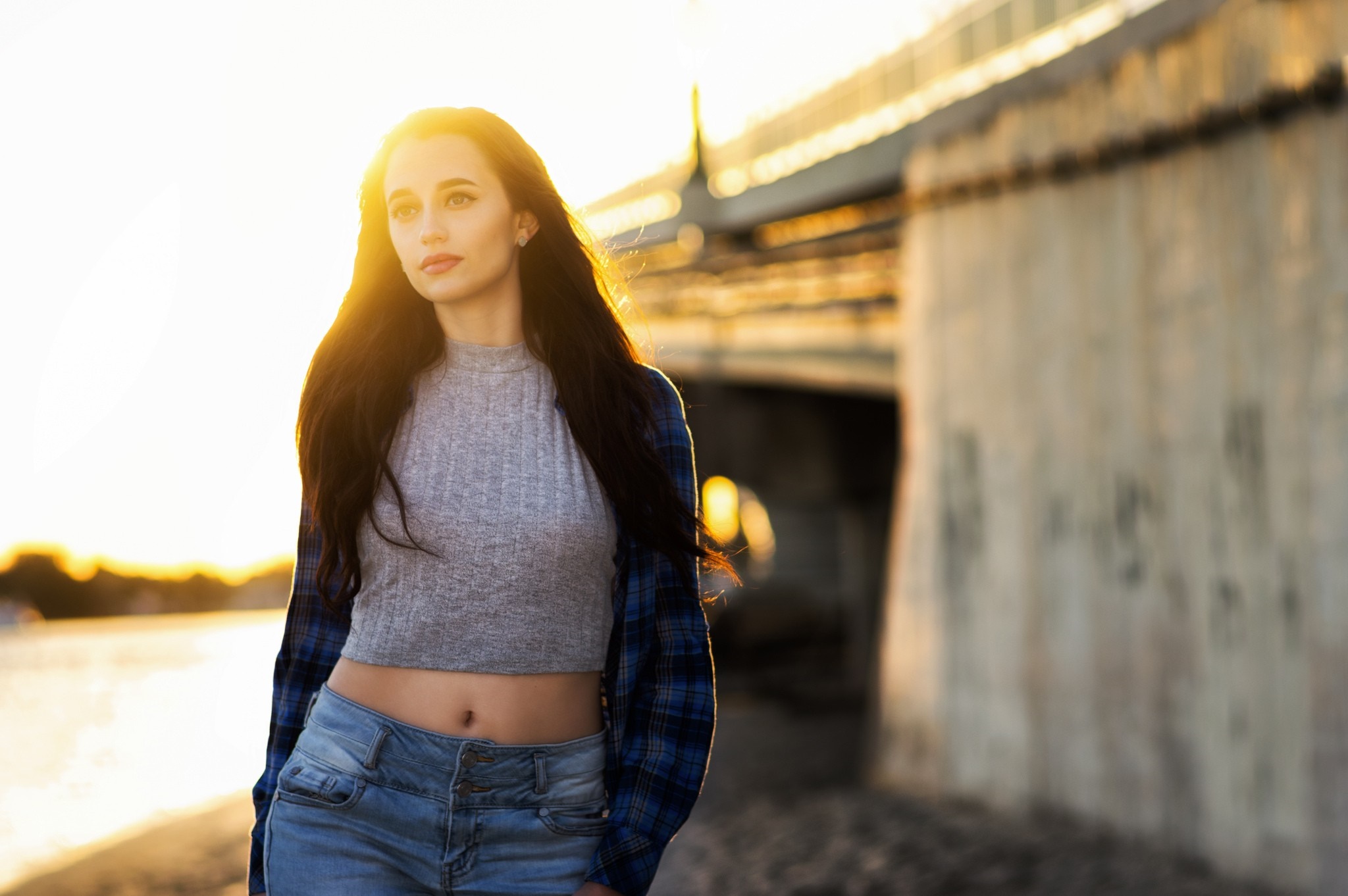 Woman in crop top and jeans standing by a bridge at sunset HD Wallpaper