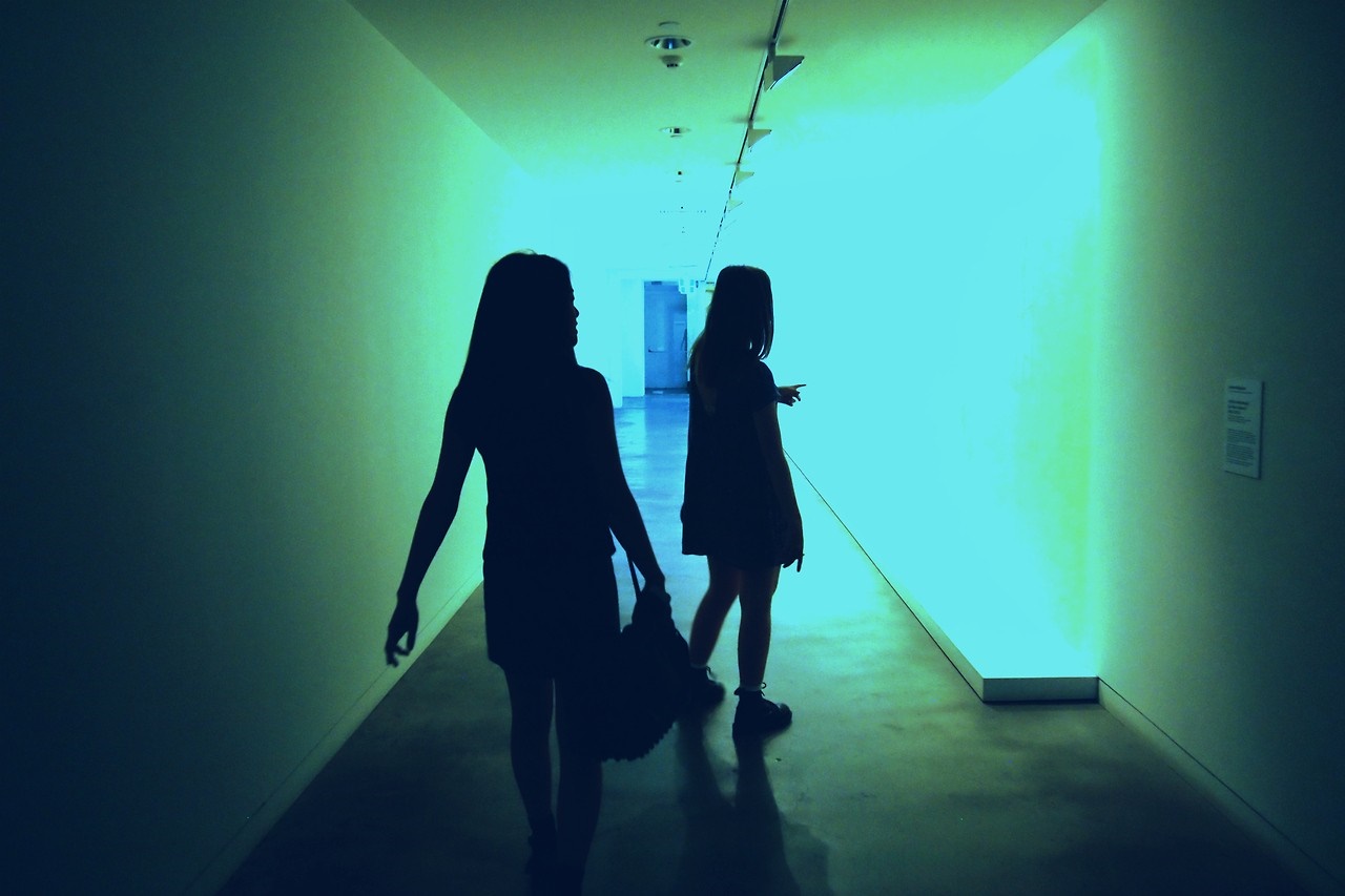 Two silhouettes walking down a brightly lit hallway HD Wallpaper
