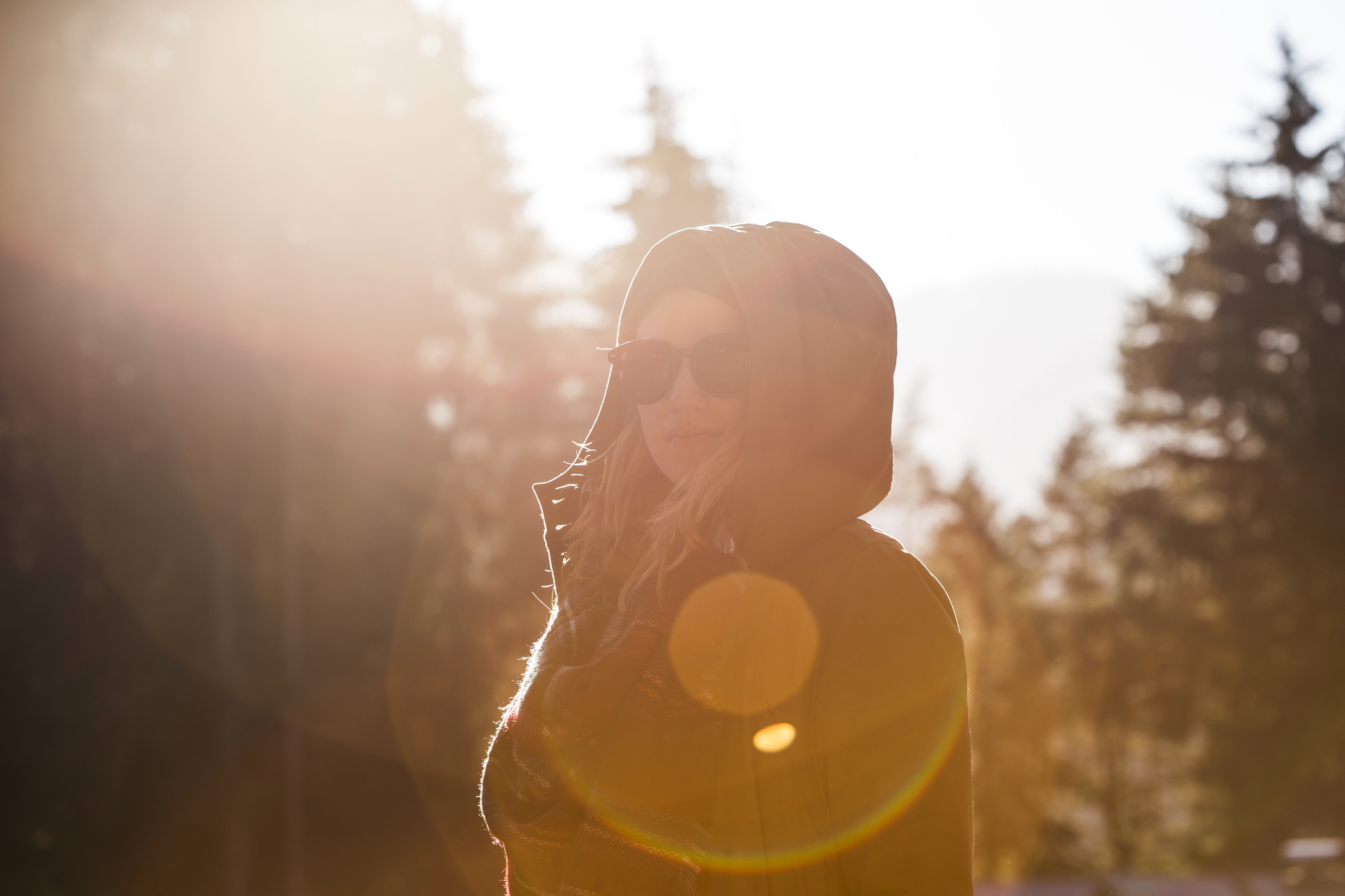 Woman in a hood with sunglasses in sunlight HD Wallpaper