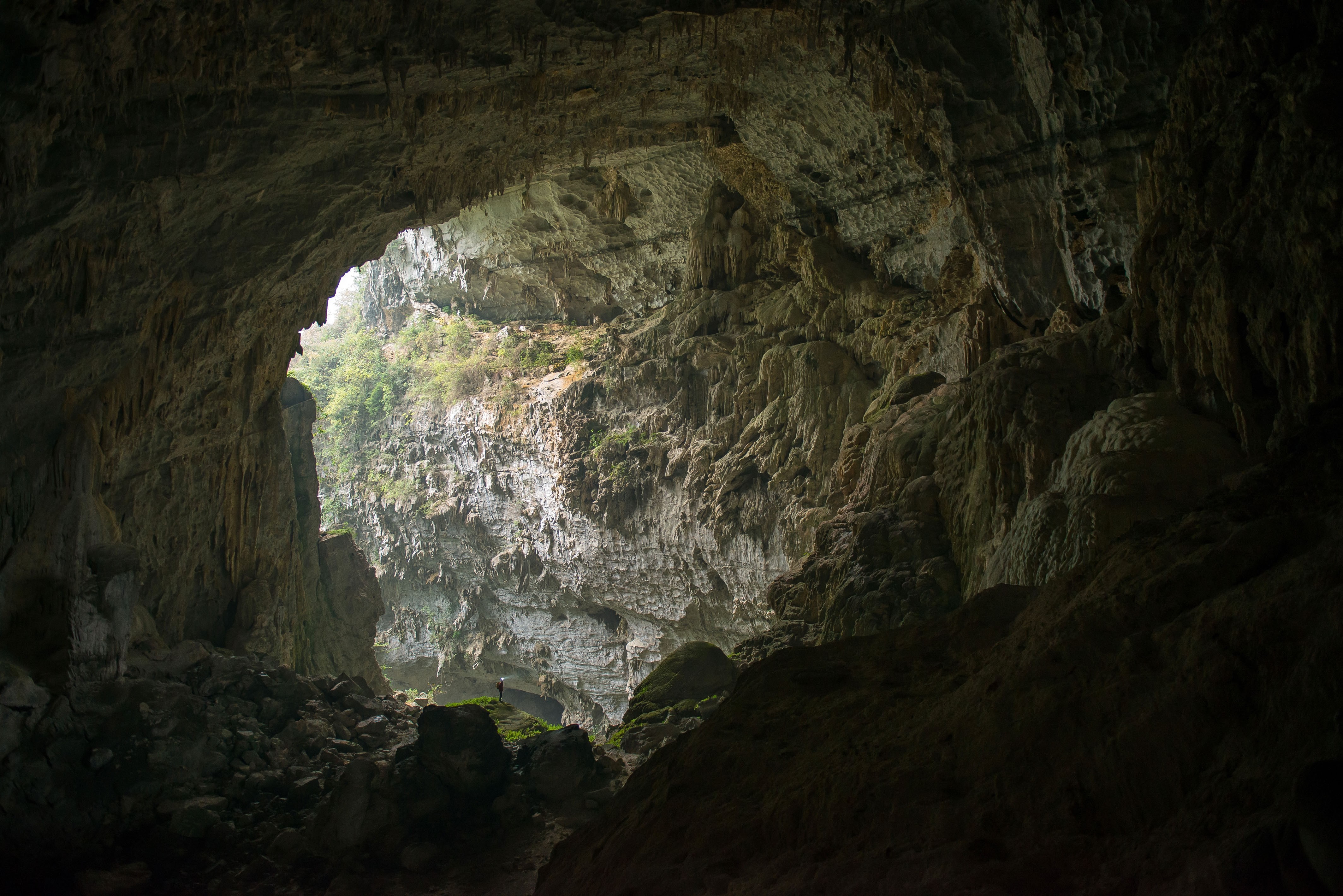 Vast cave interior with a person standing in the distance HD Wallpaper