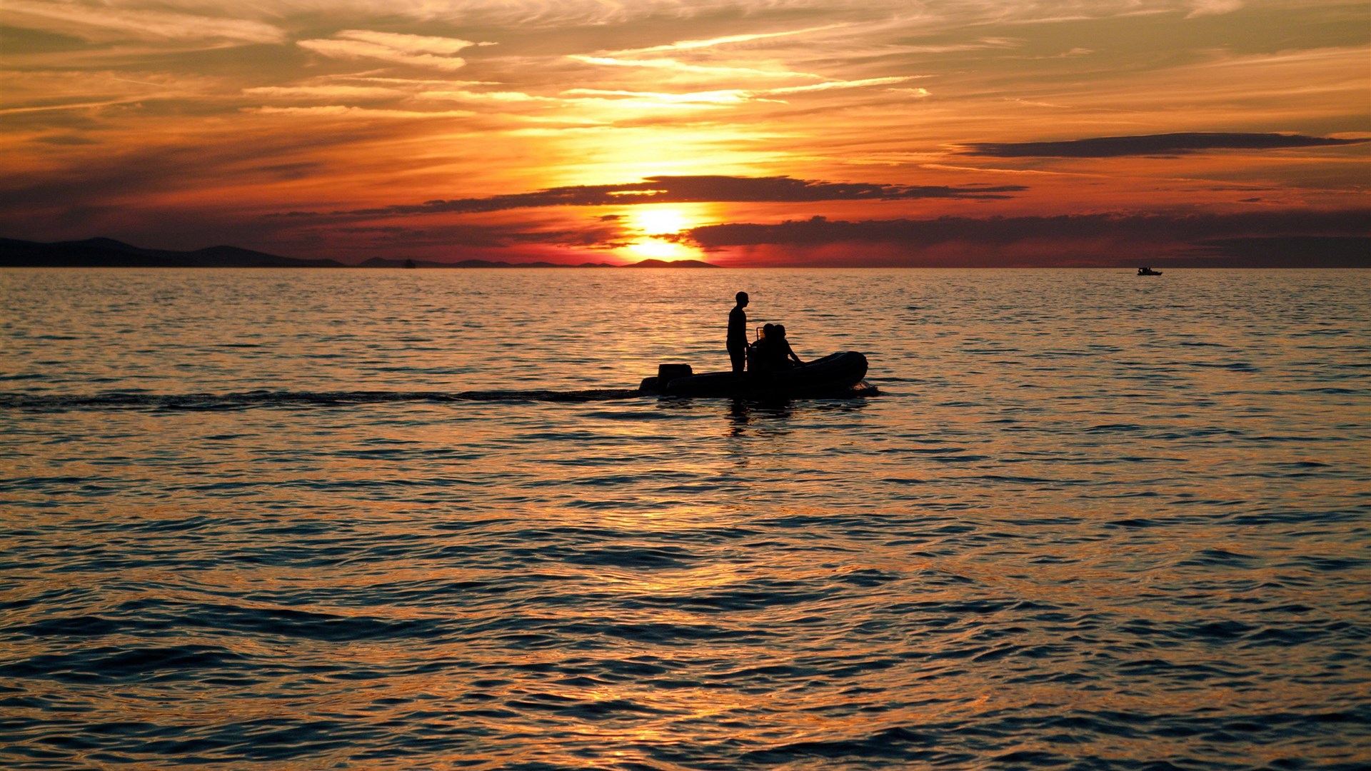 Two people in a boat at sunset over the ocean HD Wallpaper