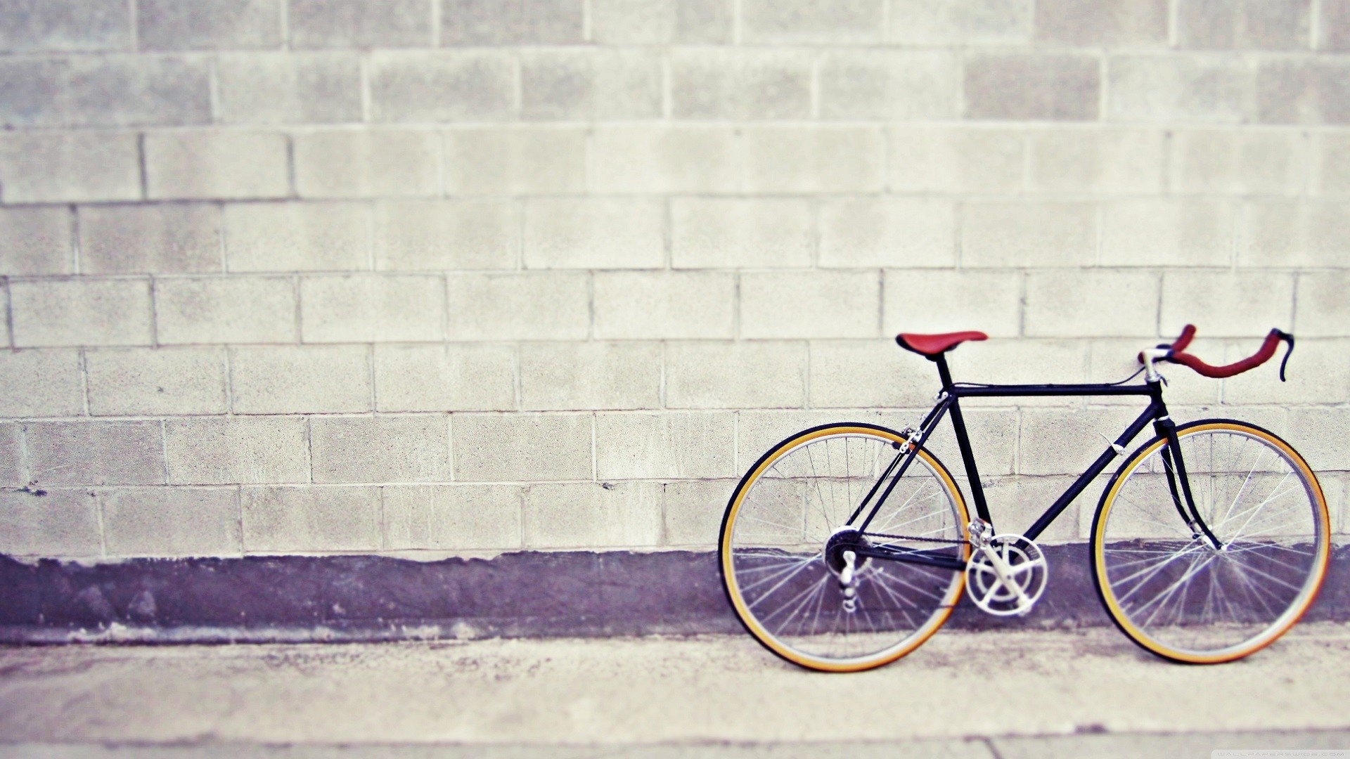 Black bicycle with red seat and handlebars against a brick wall HD Wallpaper