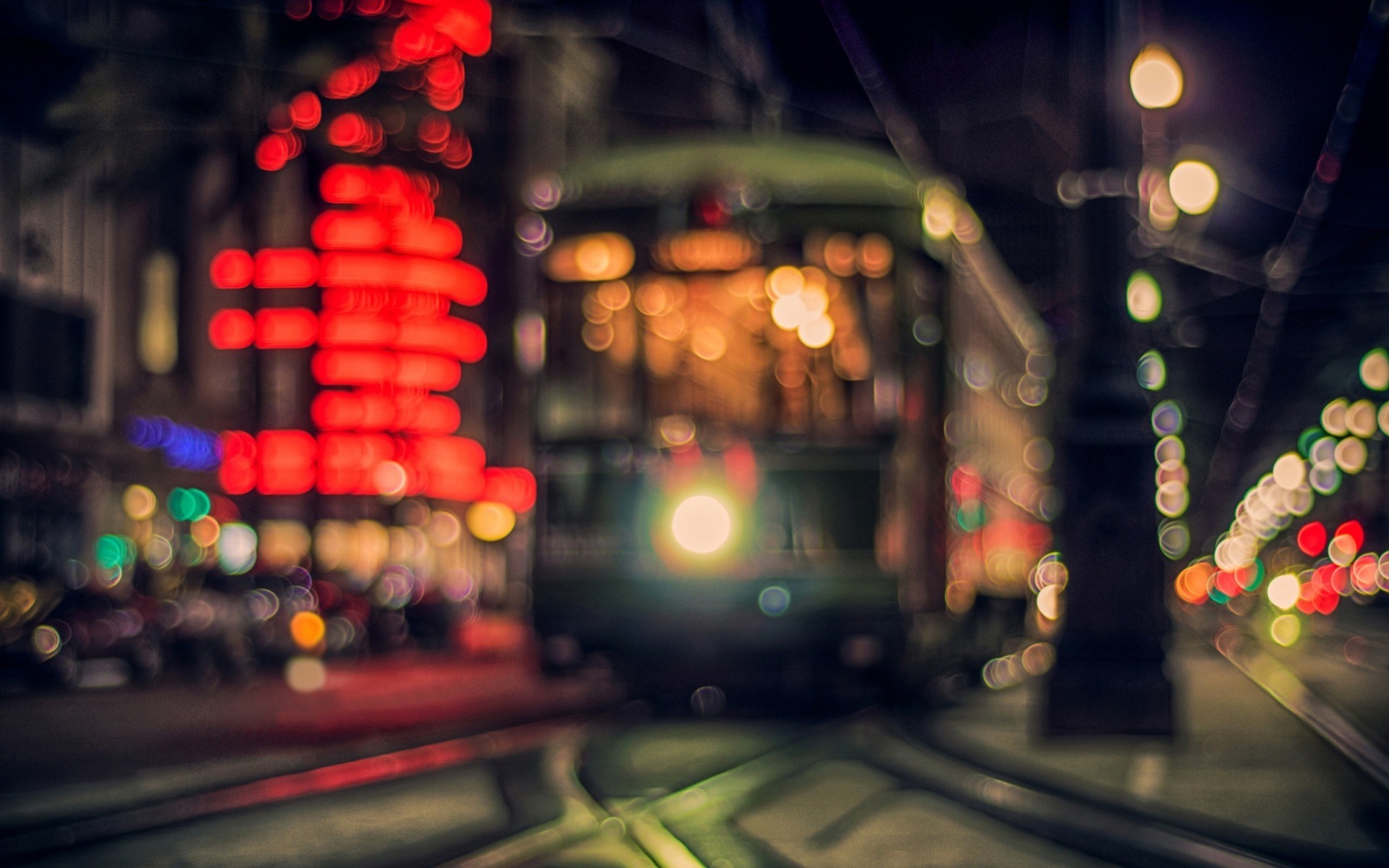 Blurred city street at night with tram and red lights HD Wallpaper