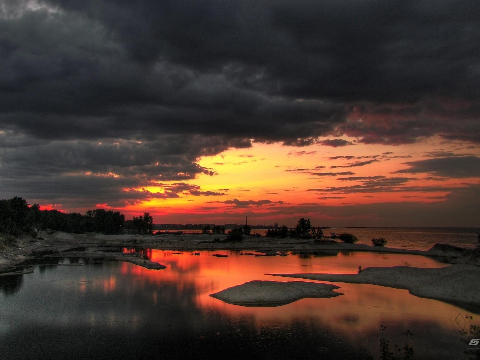 Sunset over a body of water with dark clouds HD Wallpaper