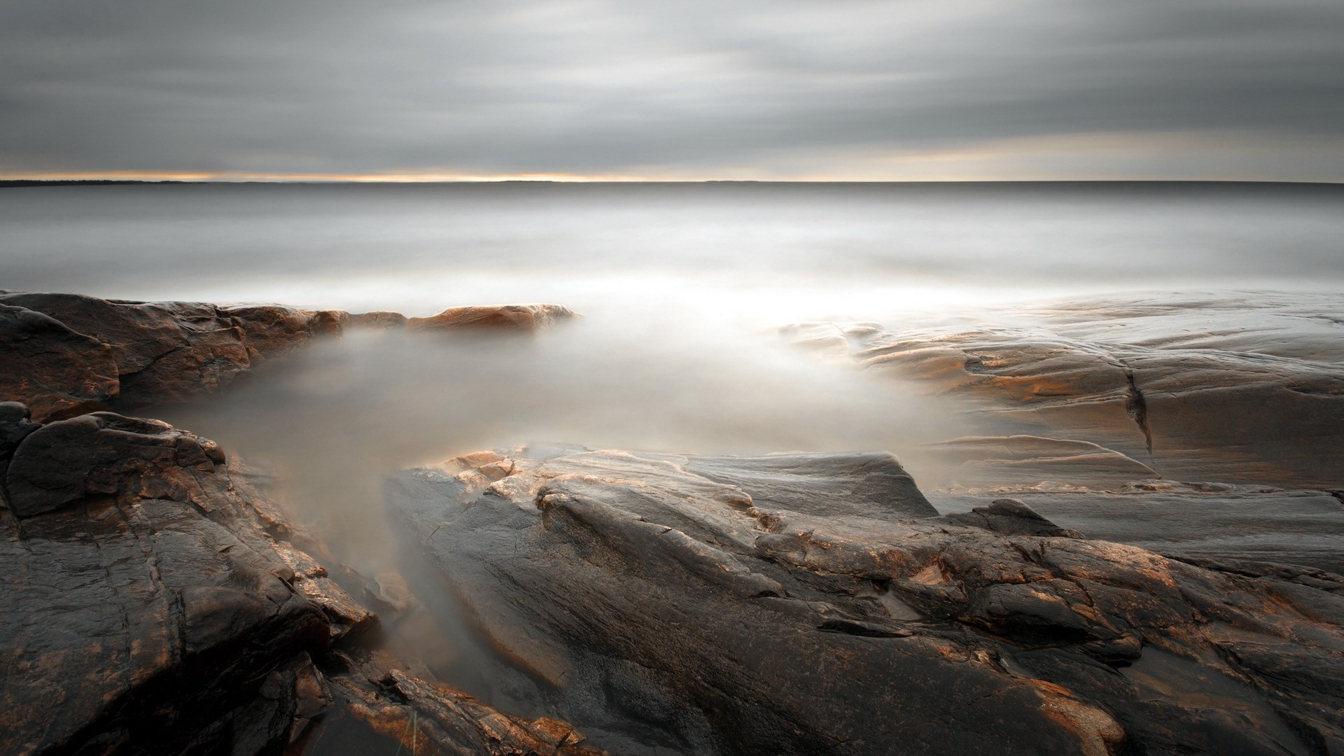 Rocky coastline with misty ocean and overcast sky HD Wallpaper