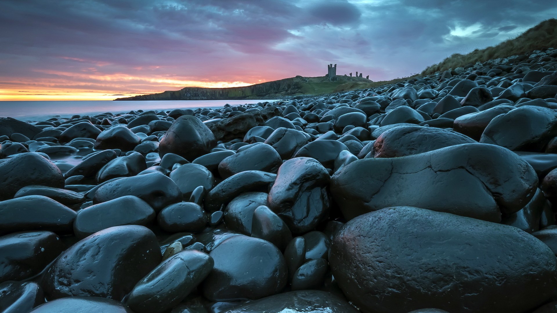 Castle ruins on a rocky beach at sunset HD Wallpaper