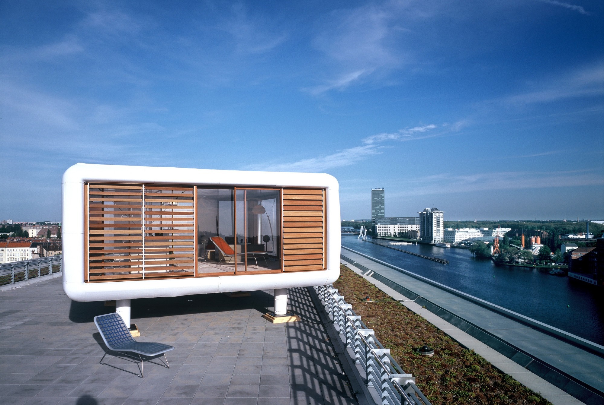 Modern pod structure on a rooftop overlooking a river and cityscape HD Wallpaper