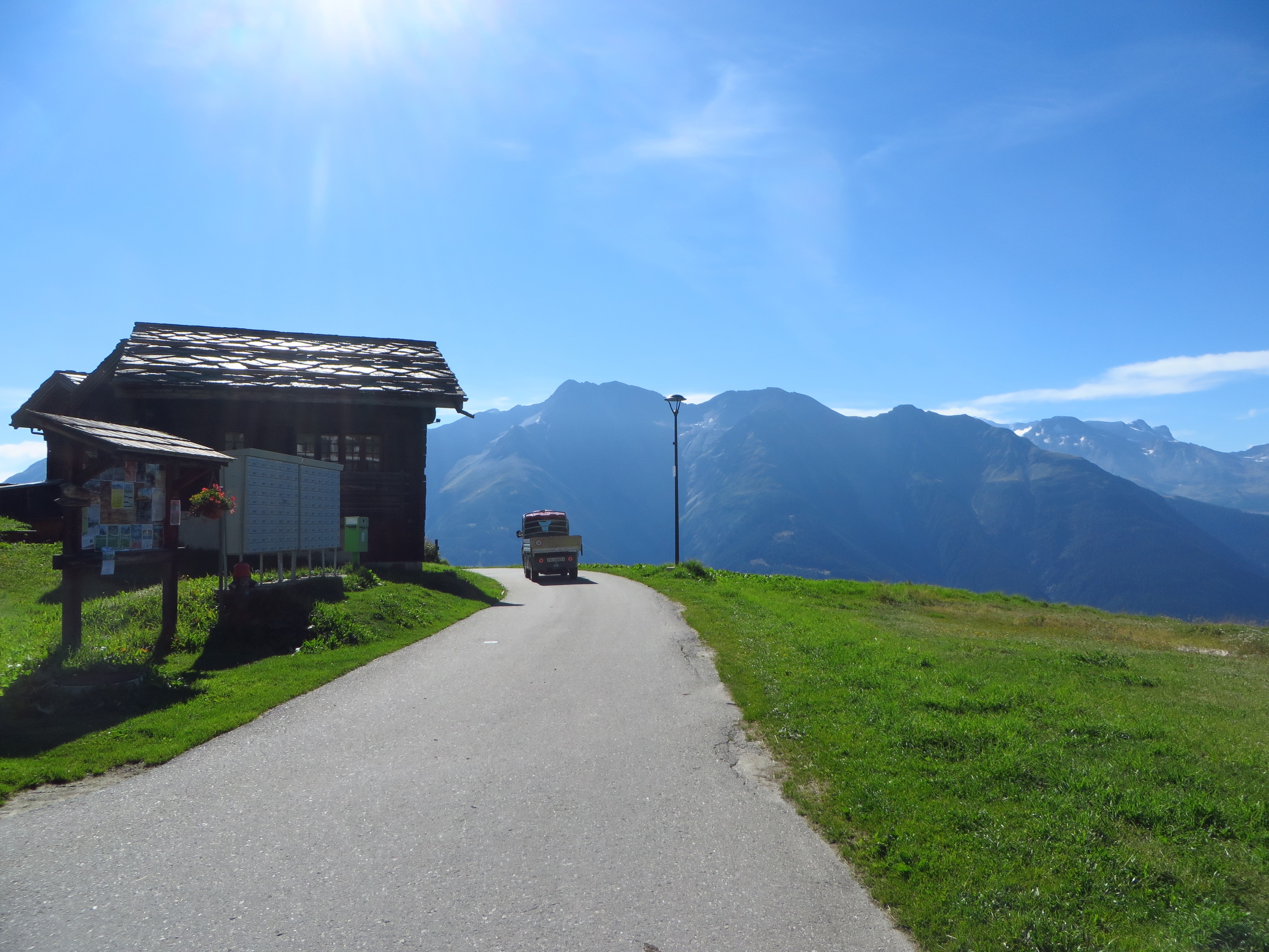 Road to the Alps with a truck and a wooden house HD Wallpaper