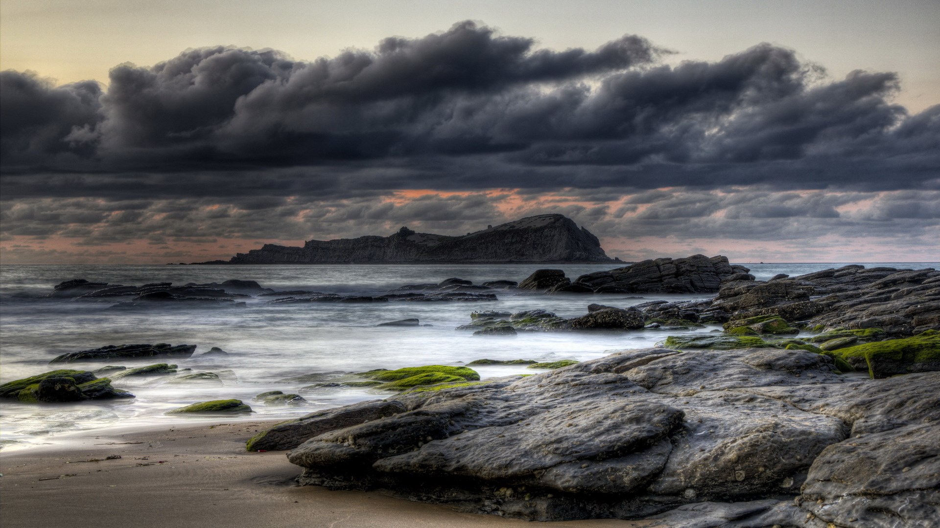 Rocky coastline with dark clouds over the ocean HD Wallpaper