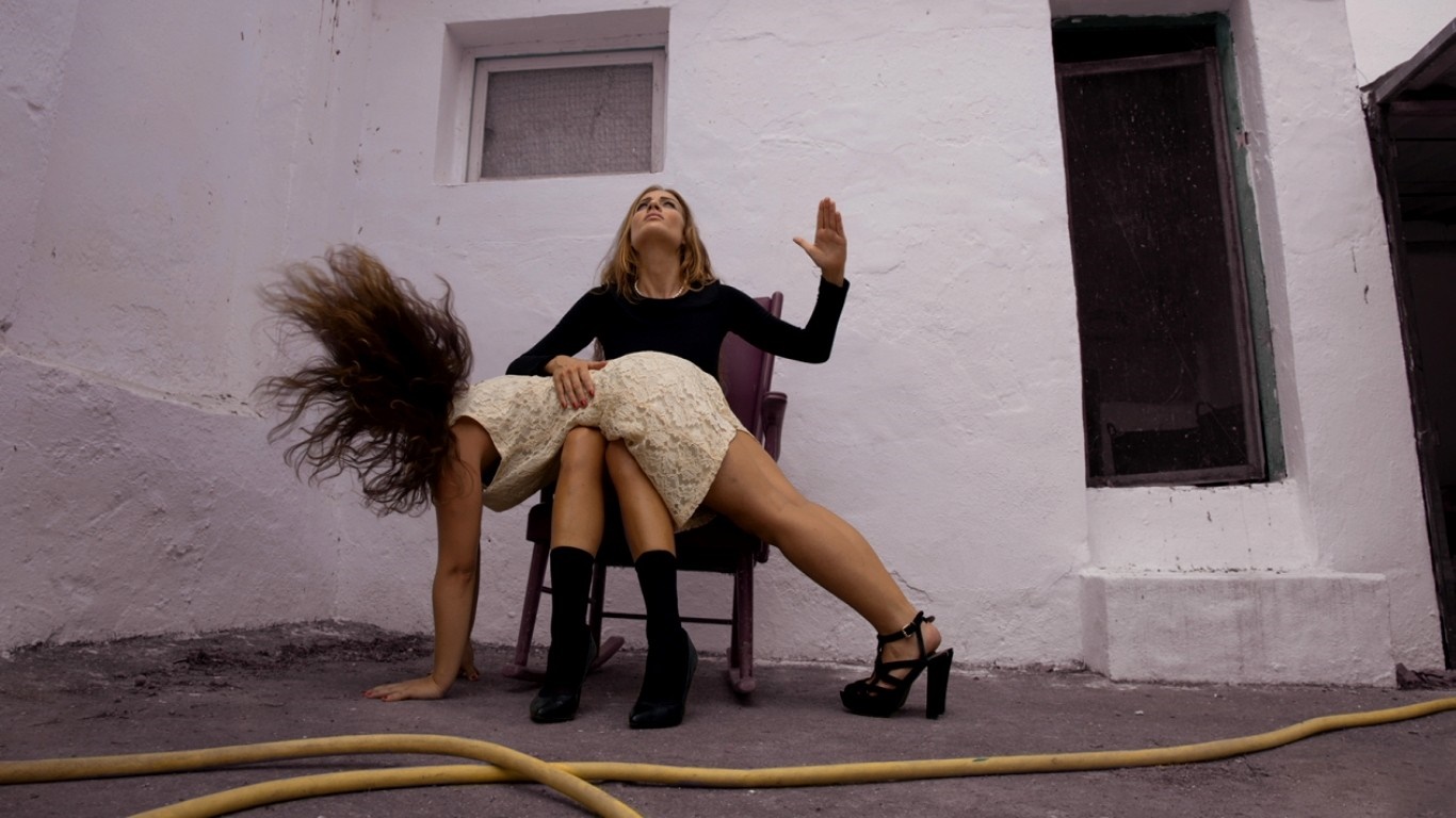 Two women in a courtyard, one spanking the other HD Wallpaper