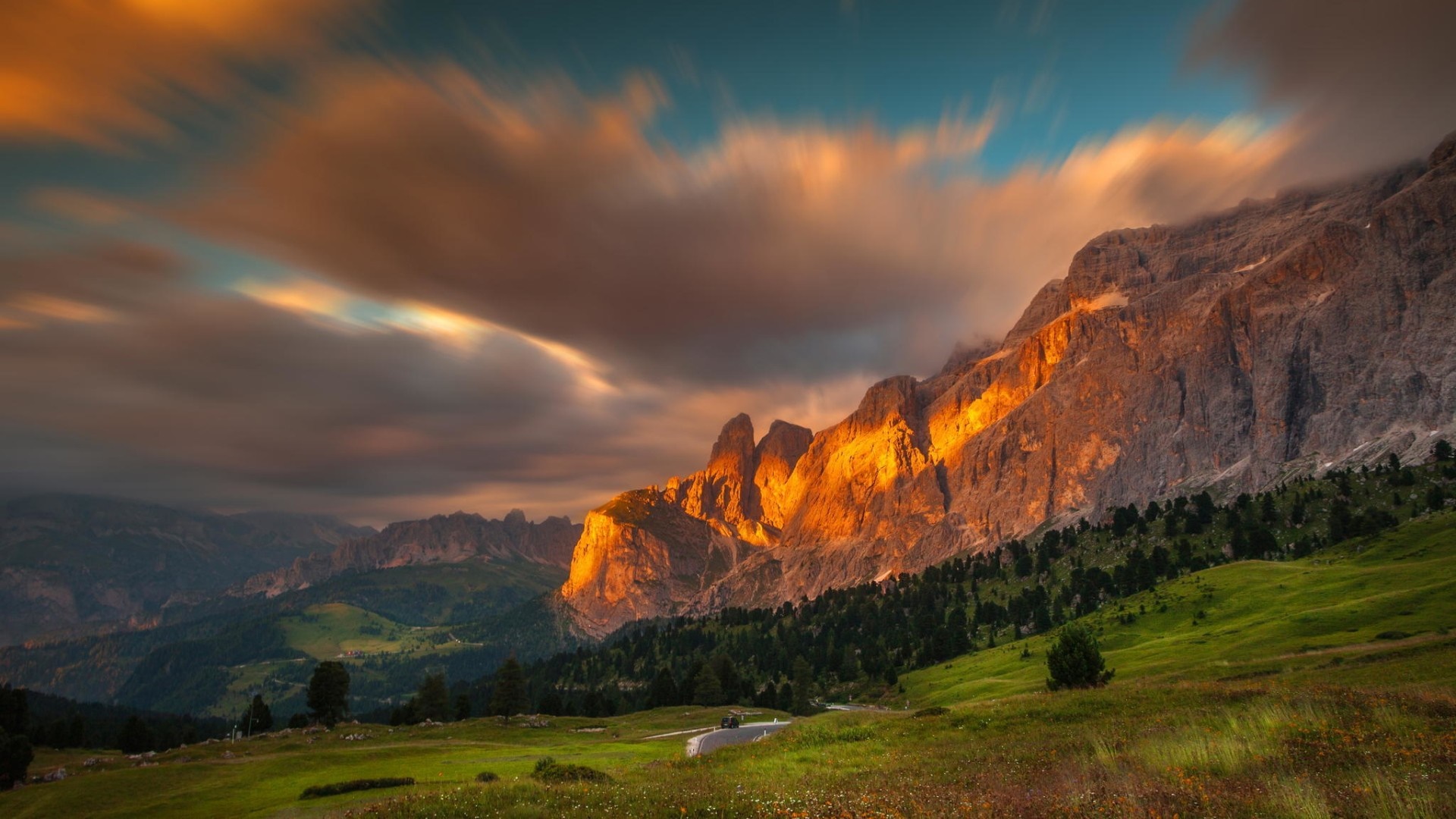 Mountain range at sunset with clouds and road HD Wallpaper