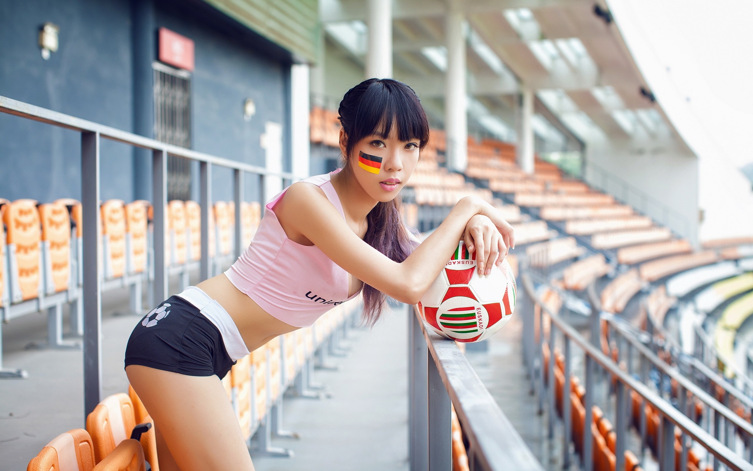Asian woman with German flag face paint at stadium HD Wallpaper