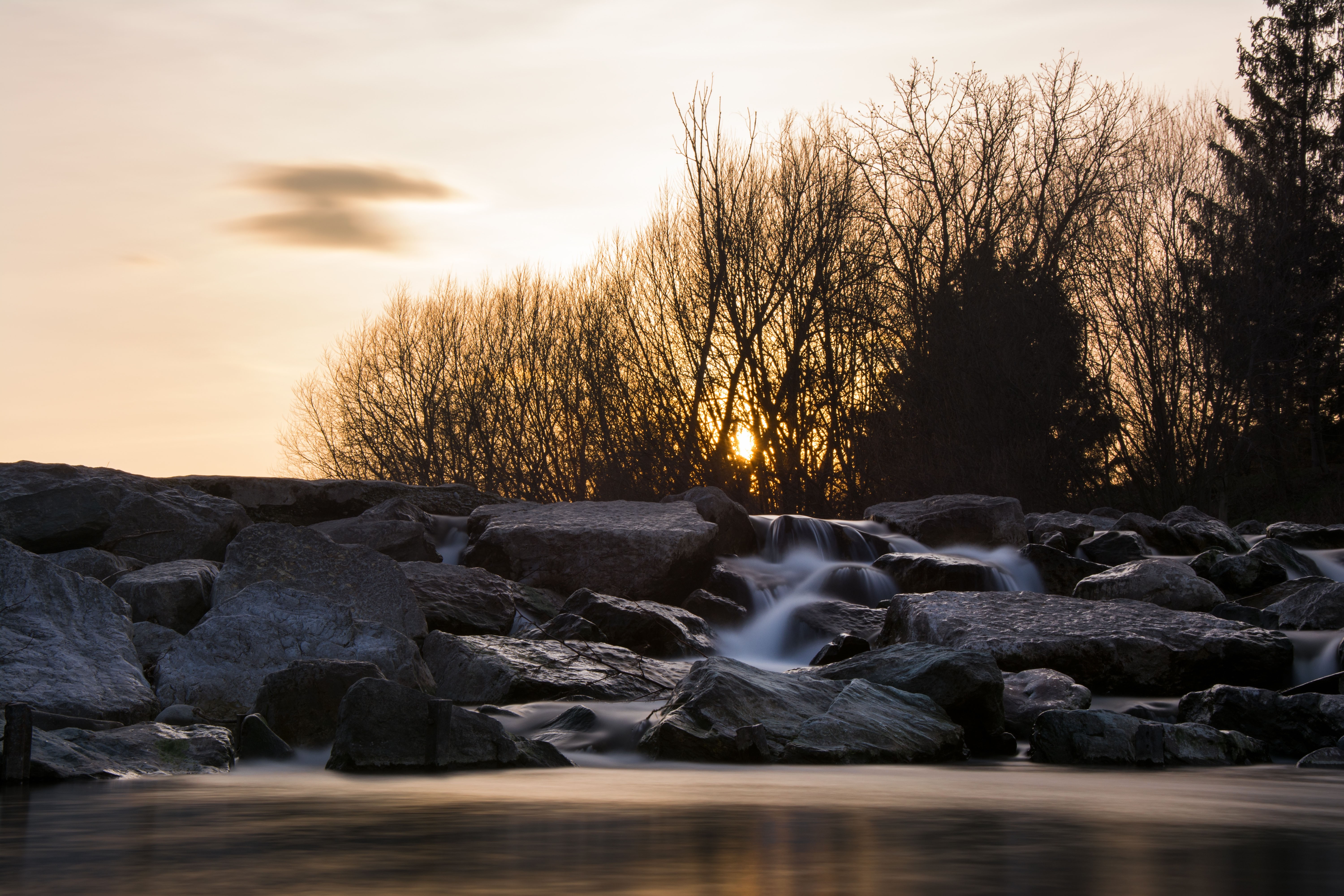 Sunset over a rocky river with bare trees HD Wallpaper