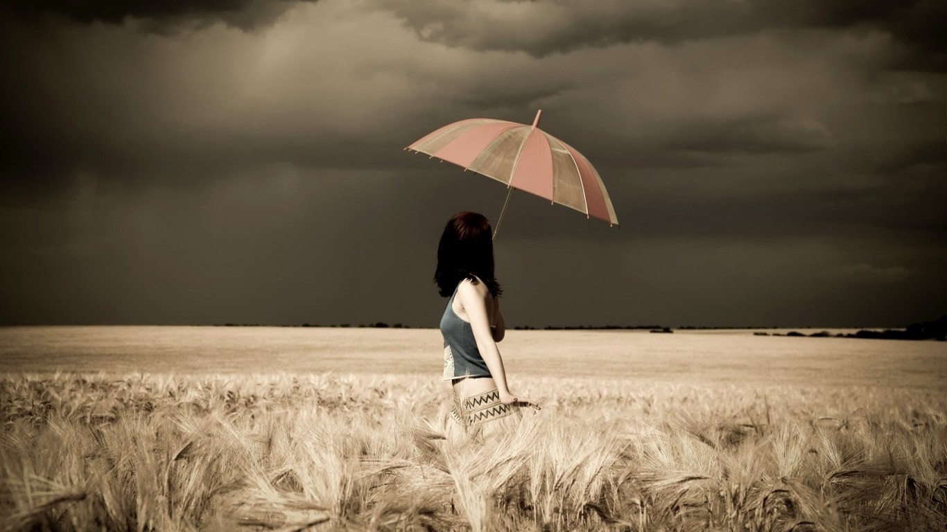 Woman with umbrella in a wheat field under stormy clouds HD Wallpaper