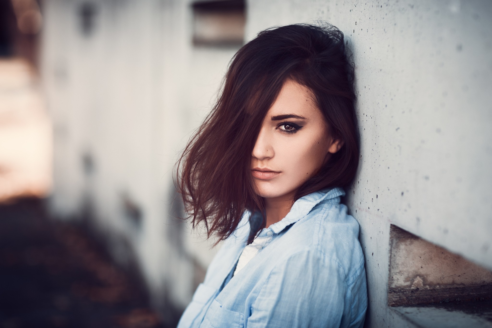Woman with dark hair leaning against a wall HD Wallpaper