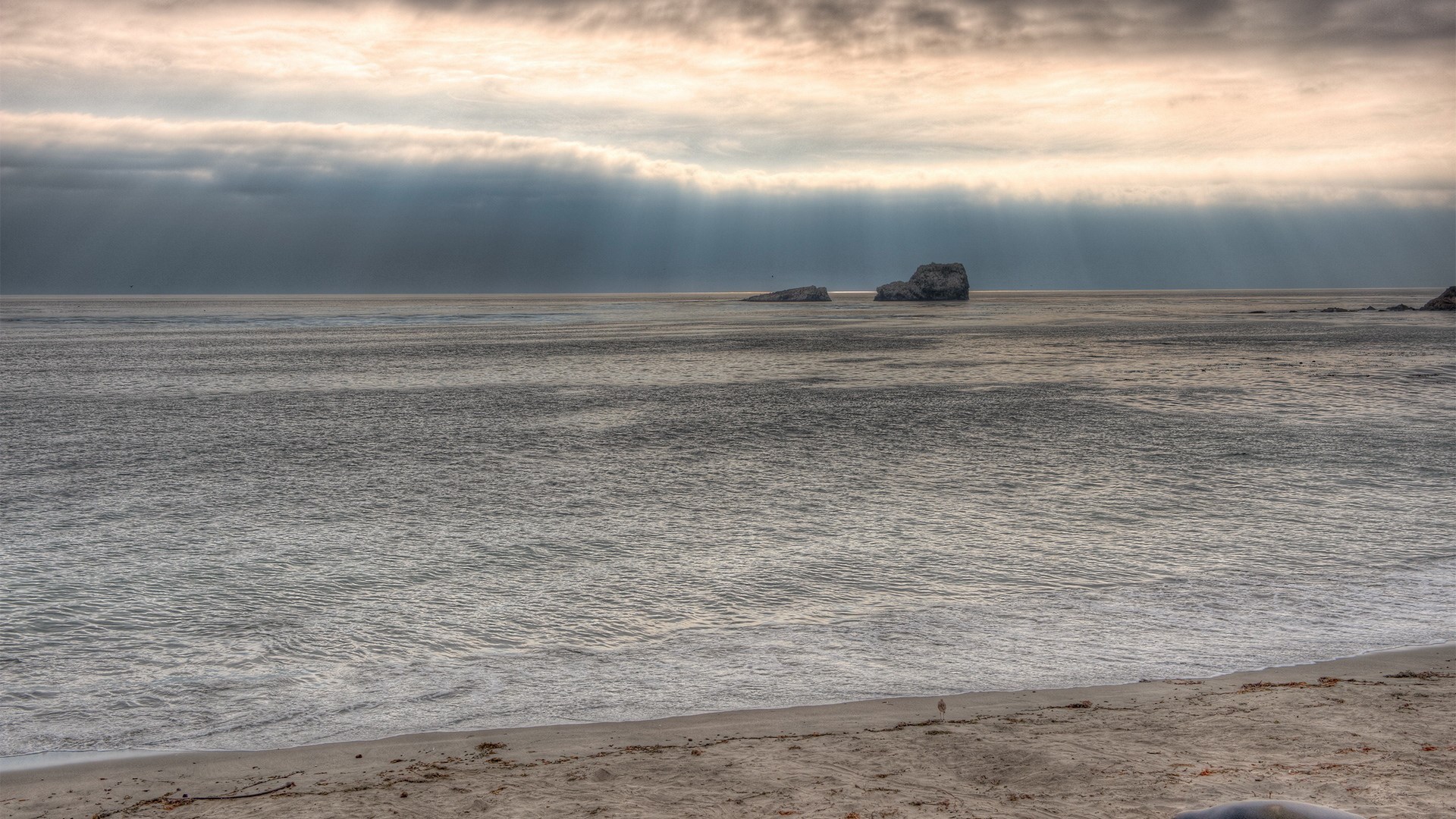 Ocean waves and rock formations under cloudy sky HD Wallpaper
